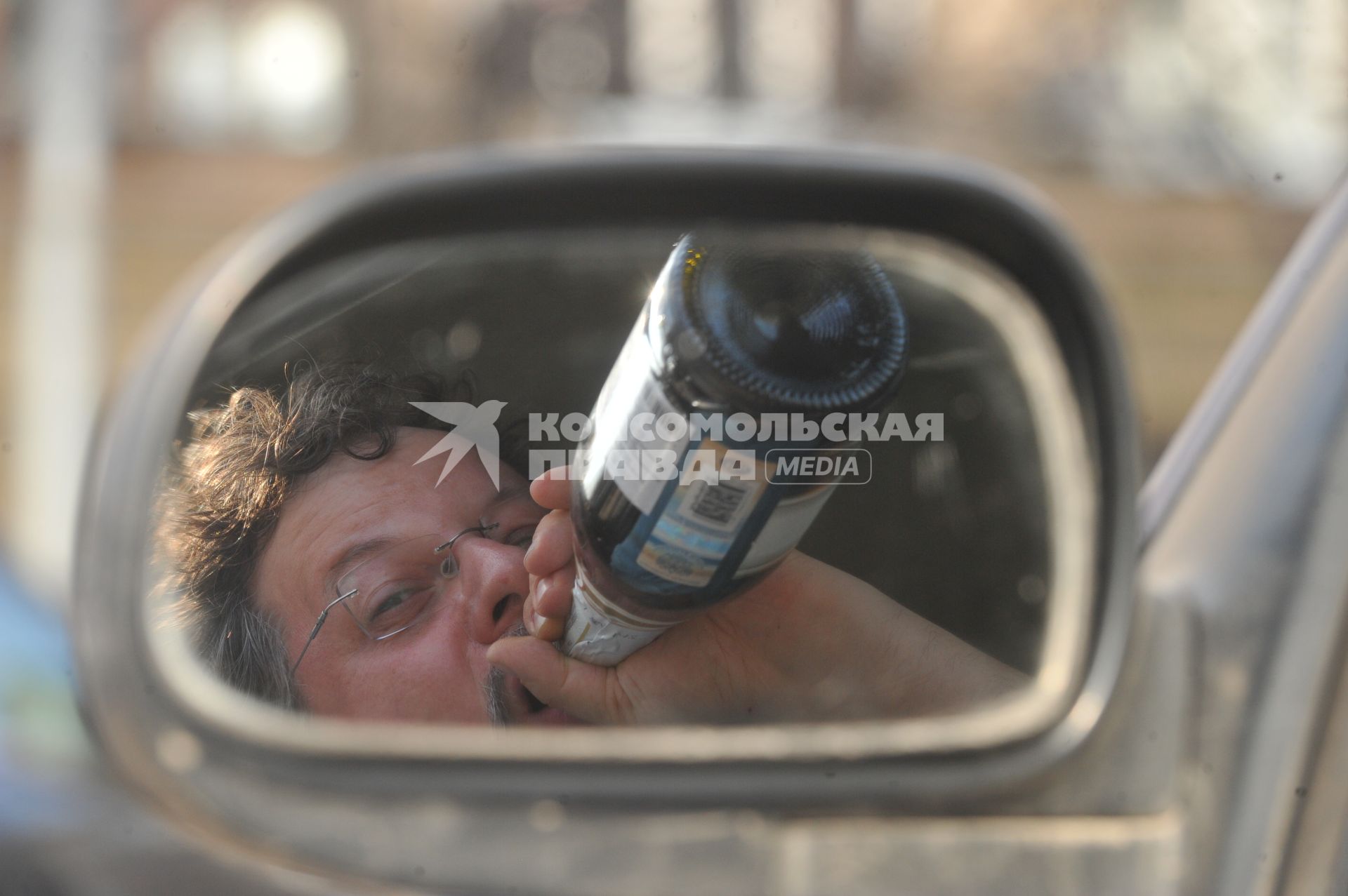 Пьянство за рулем. На снимке: водитель пьет вино в салоне автомобиля.