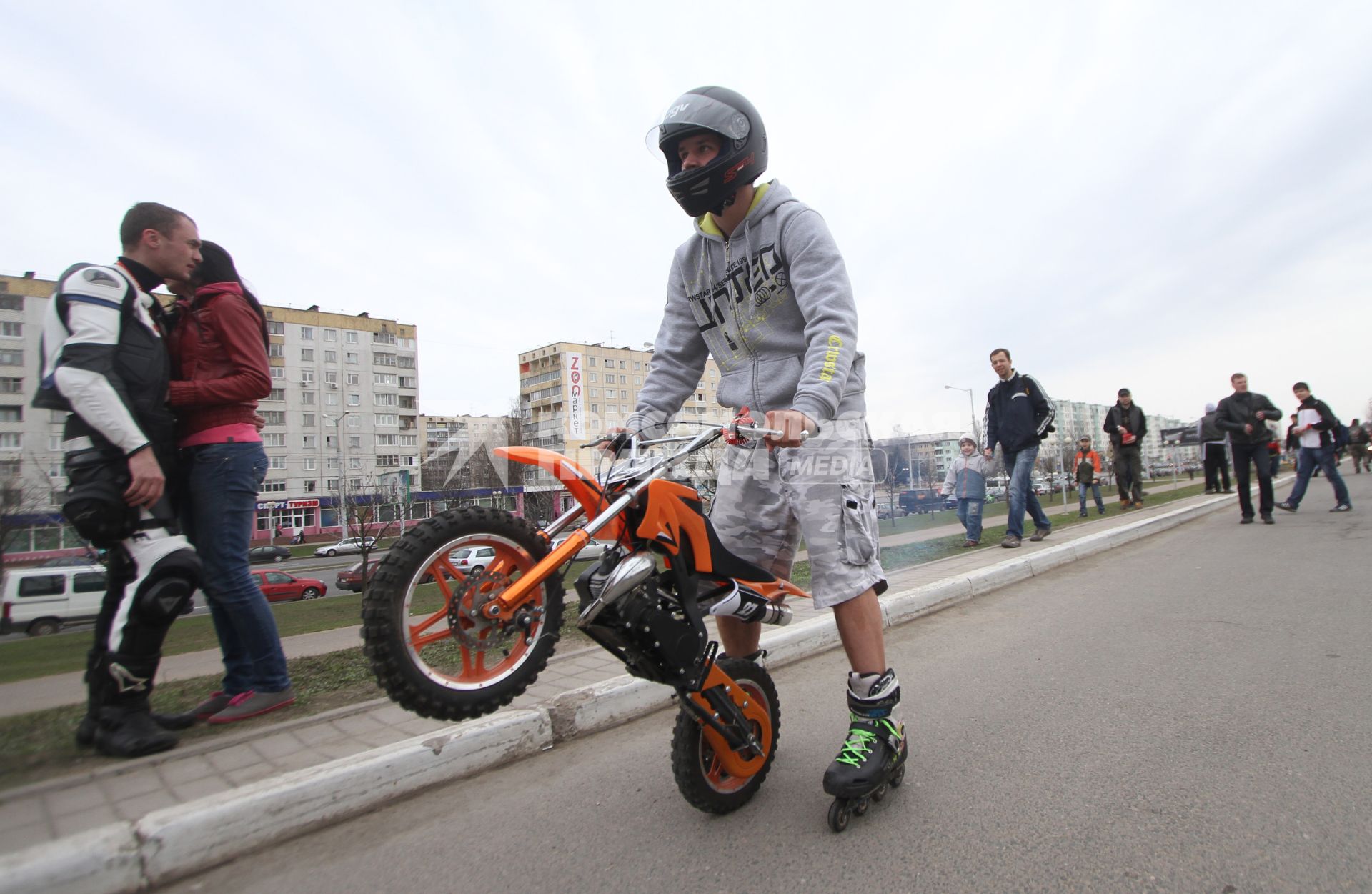 Парень в шлеме катается на роликовых коньках с мотоциклом.