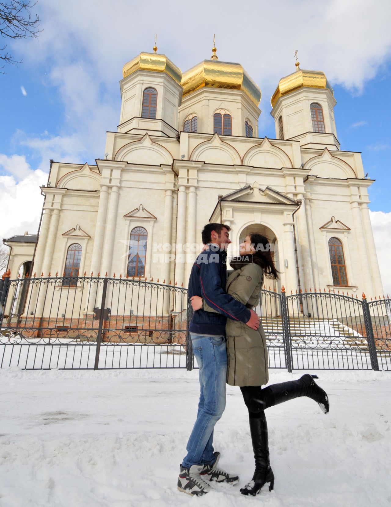 Мужчина и женщина обнимаются на фоне храма.