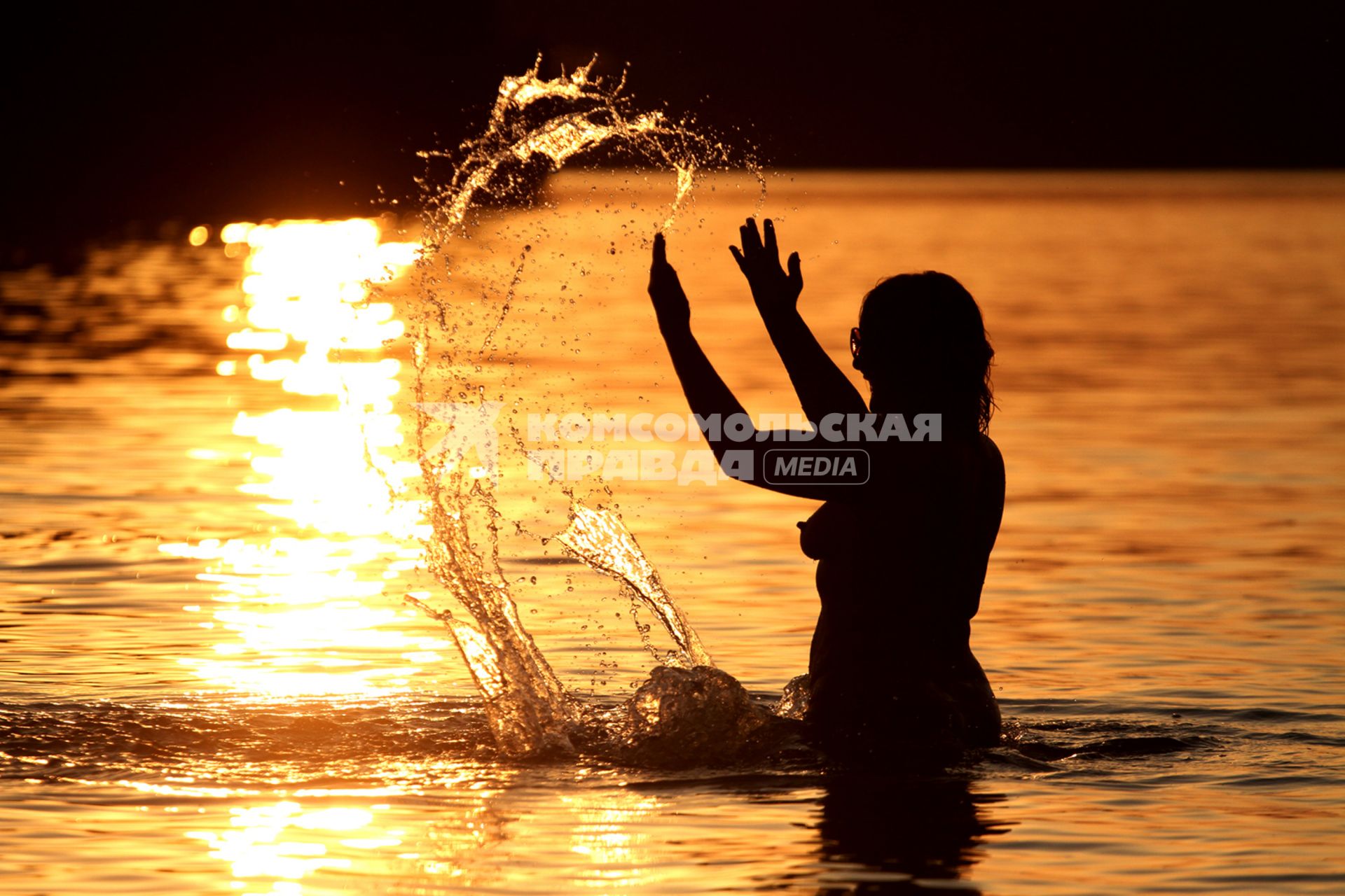 Обнаженная девушка купается на закате на Минском море