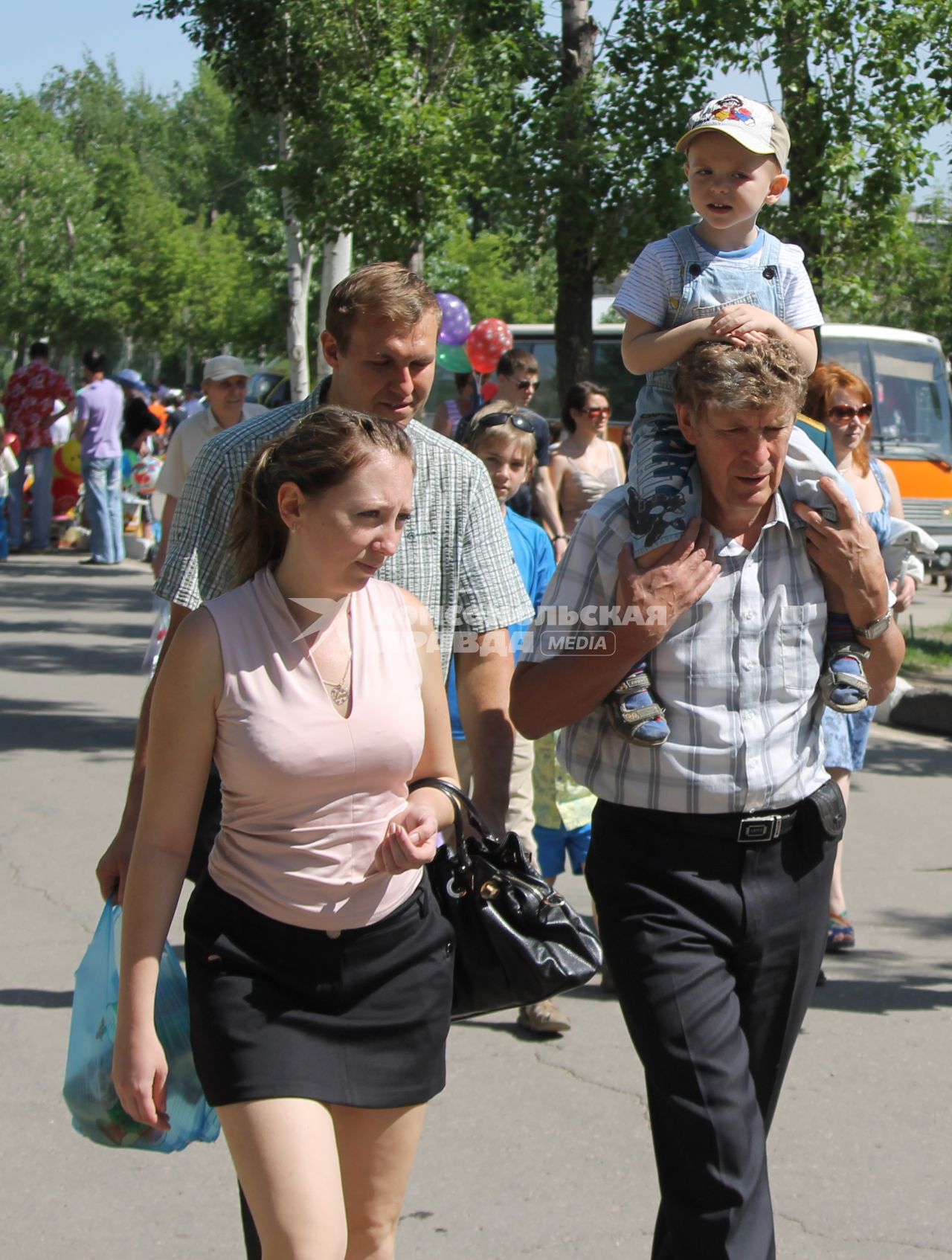 Мать и отец вышли на прогулку с сыном - отец посадил сына на плечи