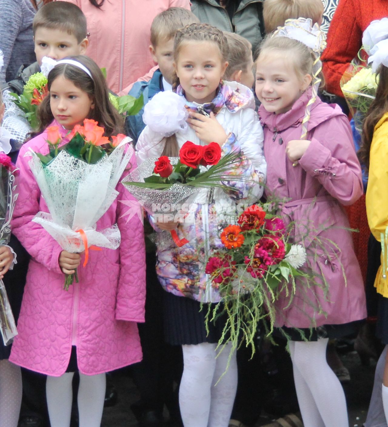 Первое сентября. Три школьницы держат в руках букеты цветов.