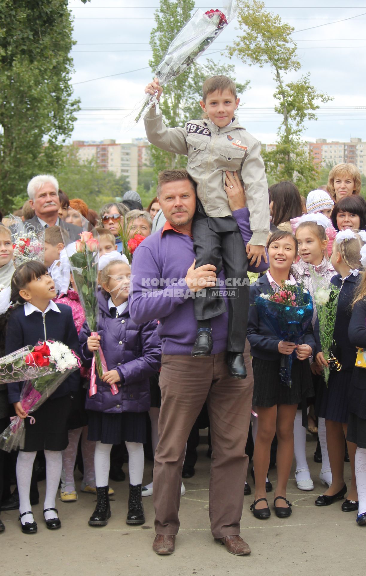 Мужчина посадил мальчика с букетом цветов на плечо