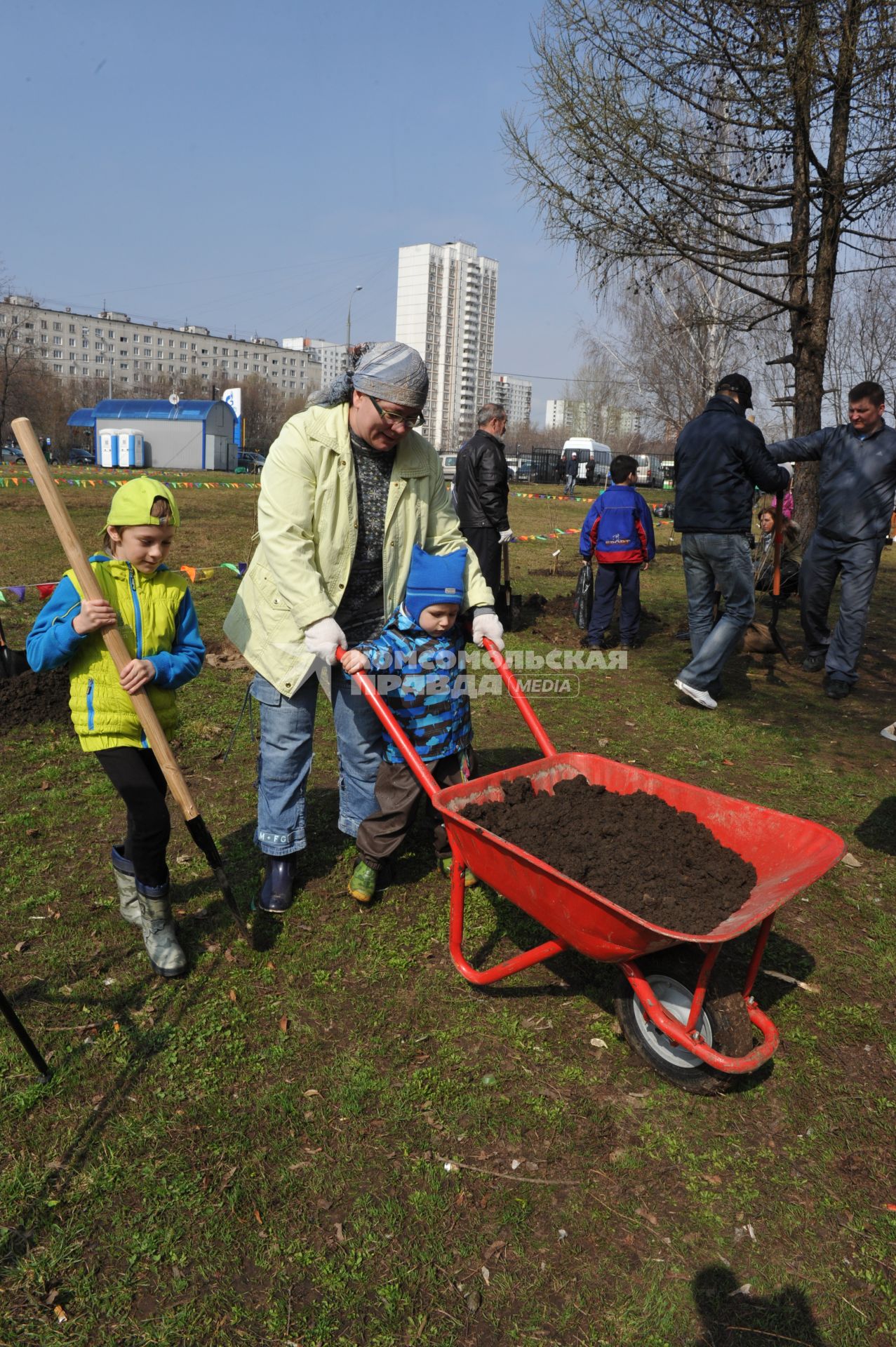 Отрадное. Общегородской субботник. На снимке:  женщина с ребенком везет тележку с землей.