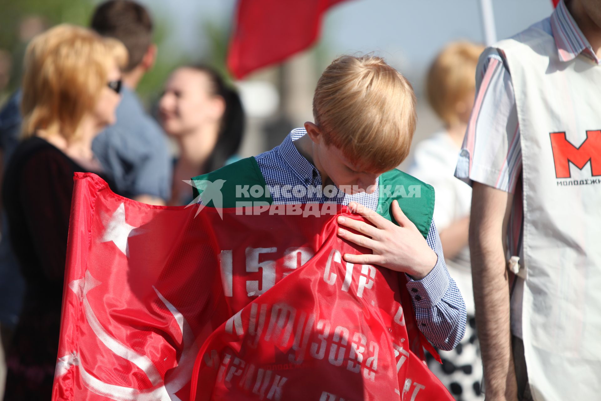 Молодой парень рассматривает красный флаг, который он держит в руках