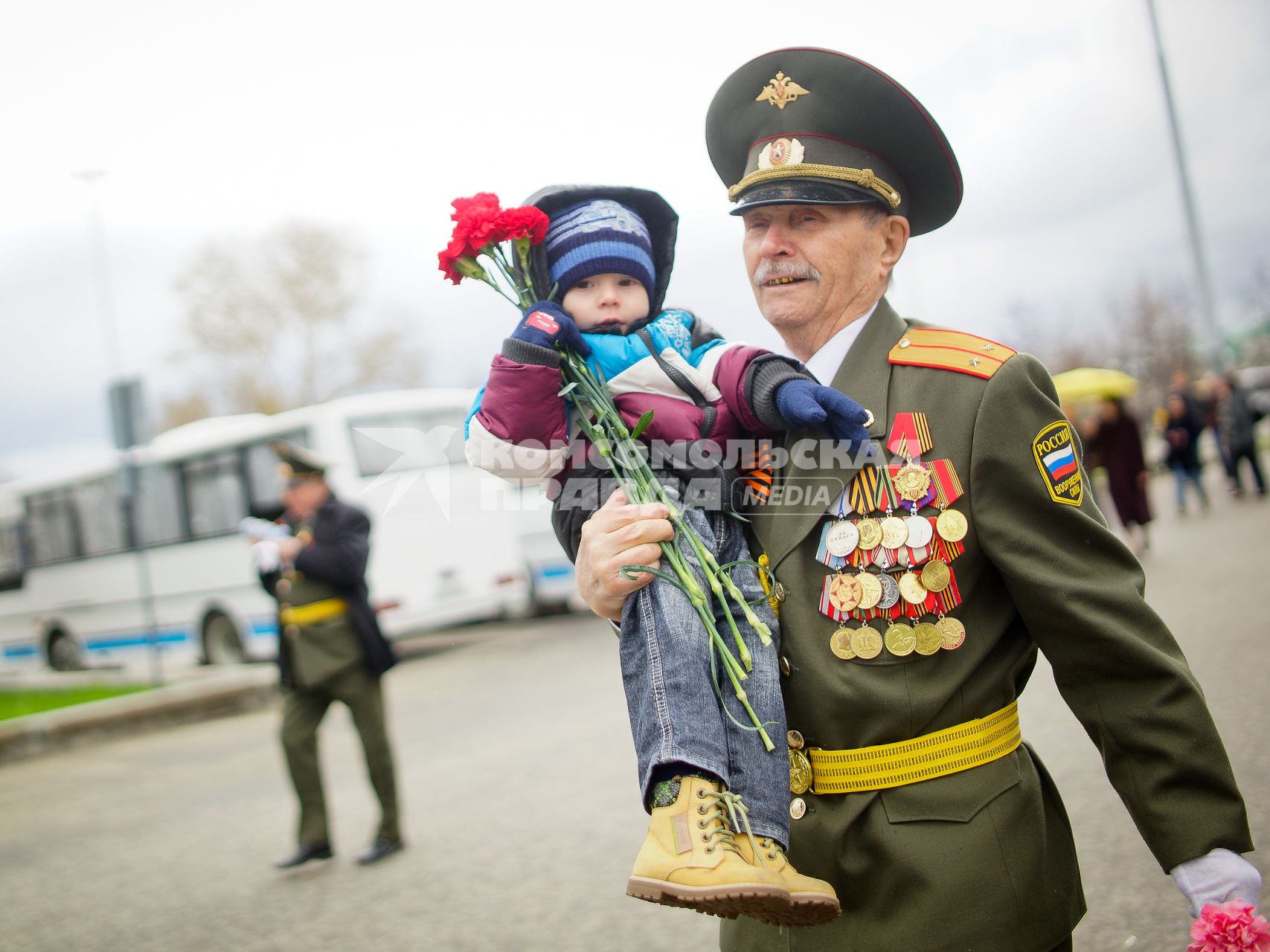 Празднование Дня Победы в Екатеринбурге. На снимке: ветеран несет на руках маленького ребенка.