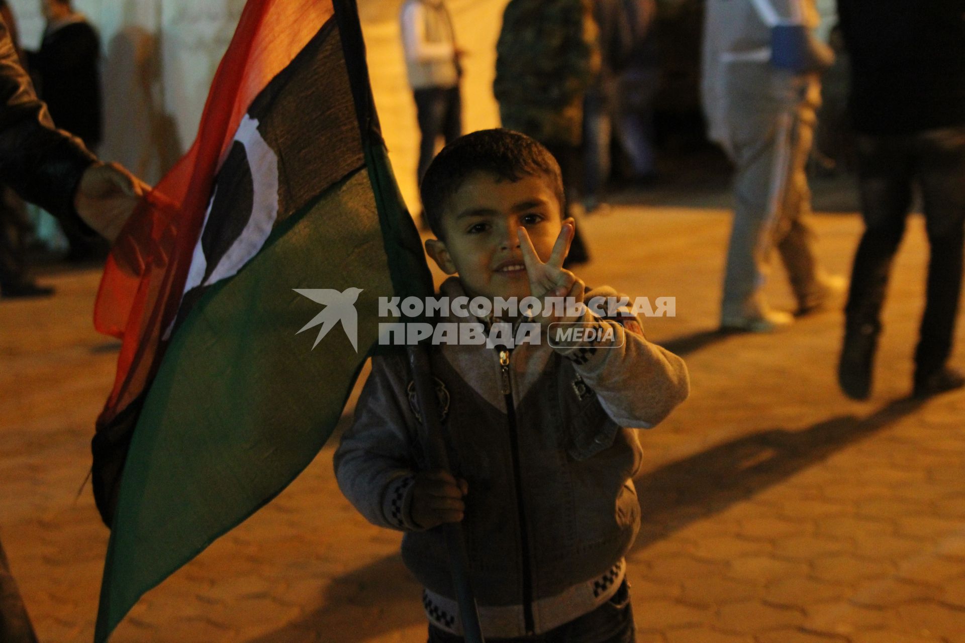 Бенгази. Гражданская война в Ливии - `Арабская весна`. `Площадь Свободы`. Митинг оппозиции. На снимке: ливийский мальчик держит  национальный флаг и демонстрирует жест Victory (Победа).