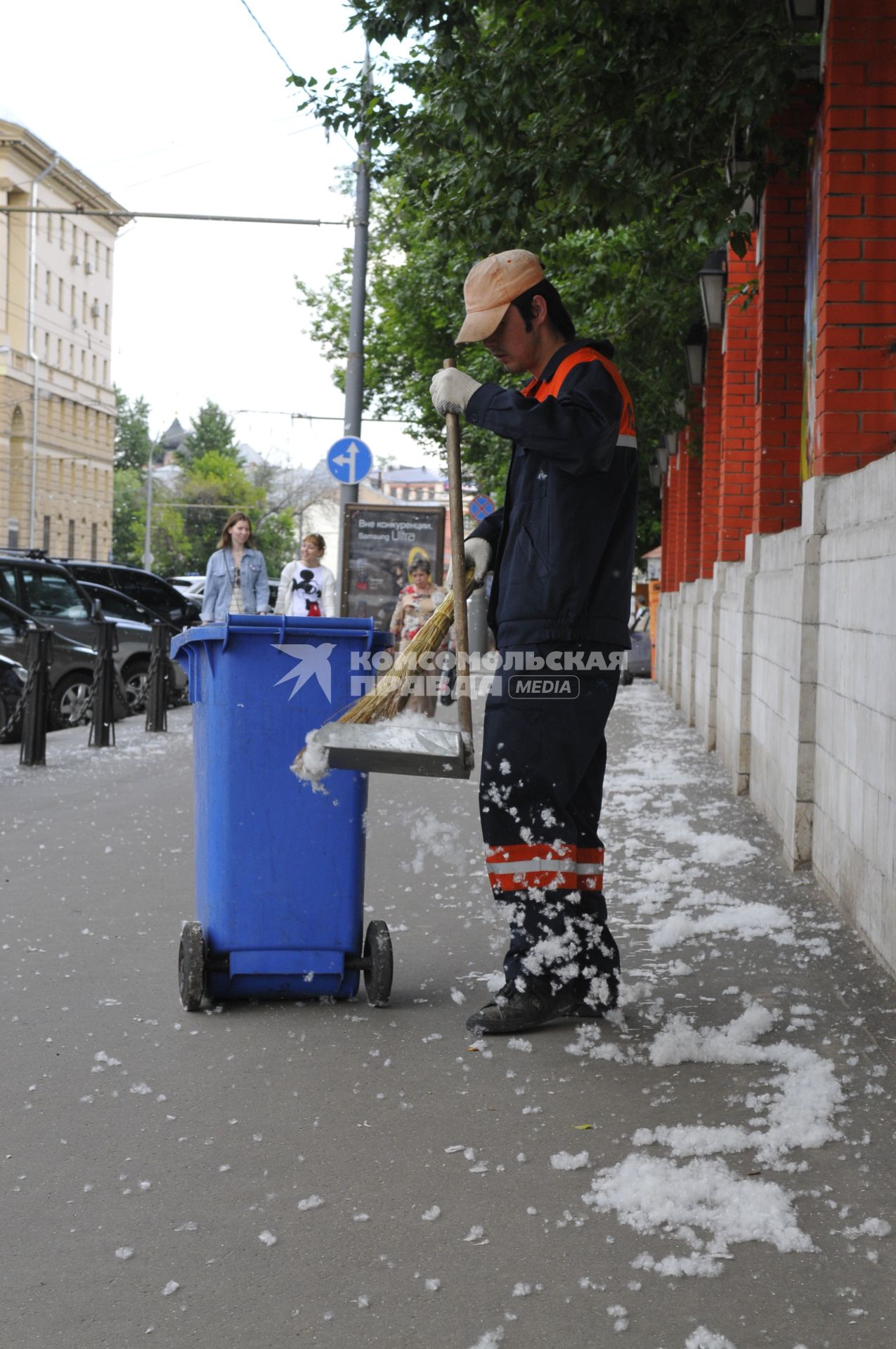 Тополиный пух в городе. На снимке: гастарбайтер убирает пух с улицы.