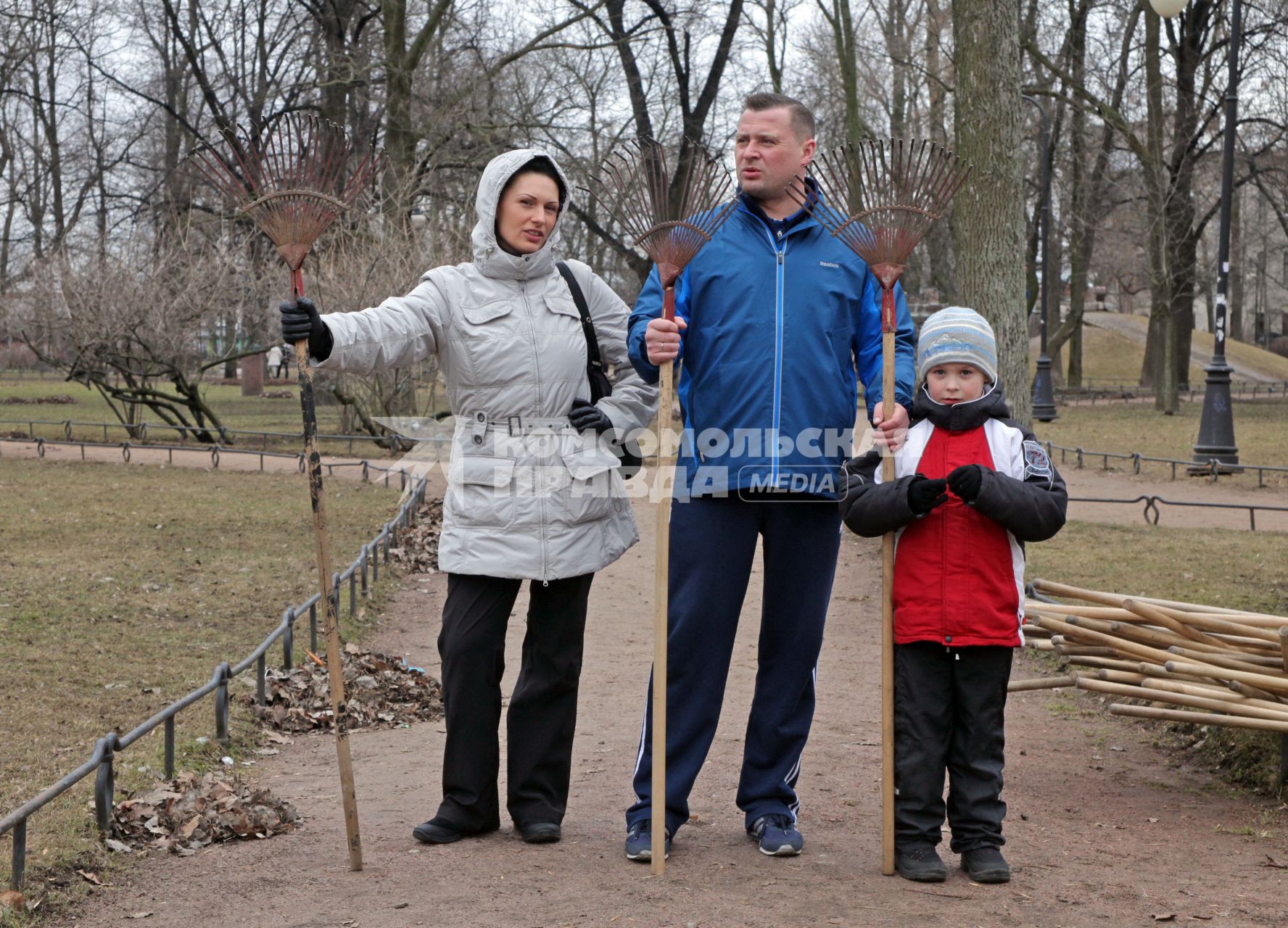 Семья с граблями готовится к уборке парка.