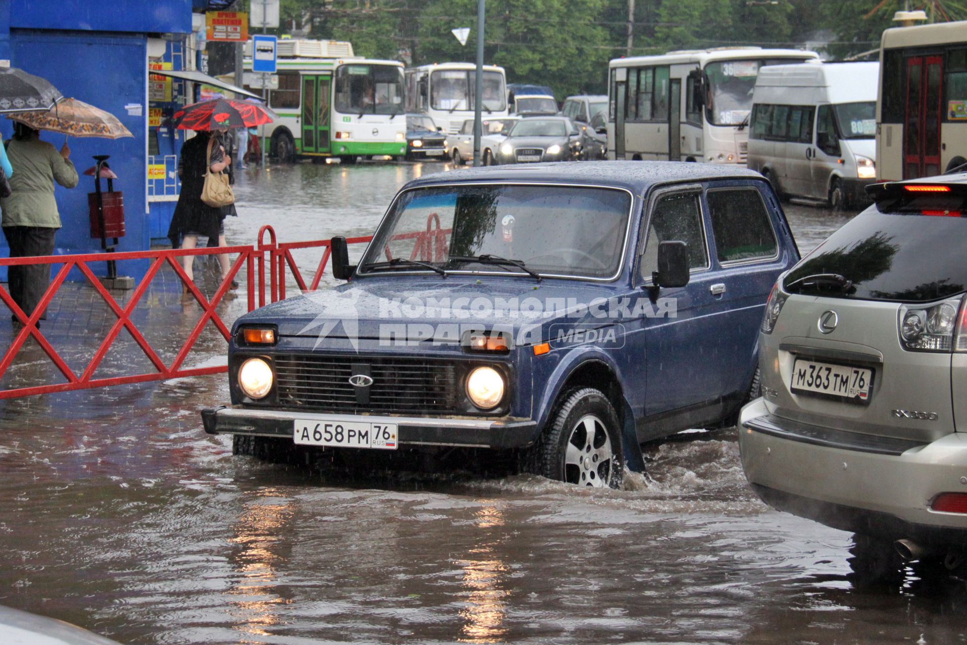 Последствия ливня в городе - затопленные улицы. Автомобиль едет по затопленной улице.