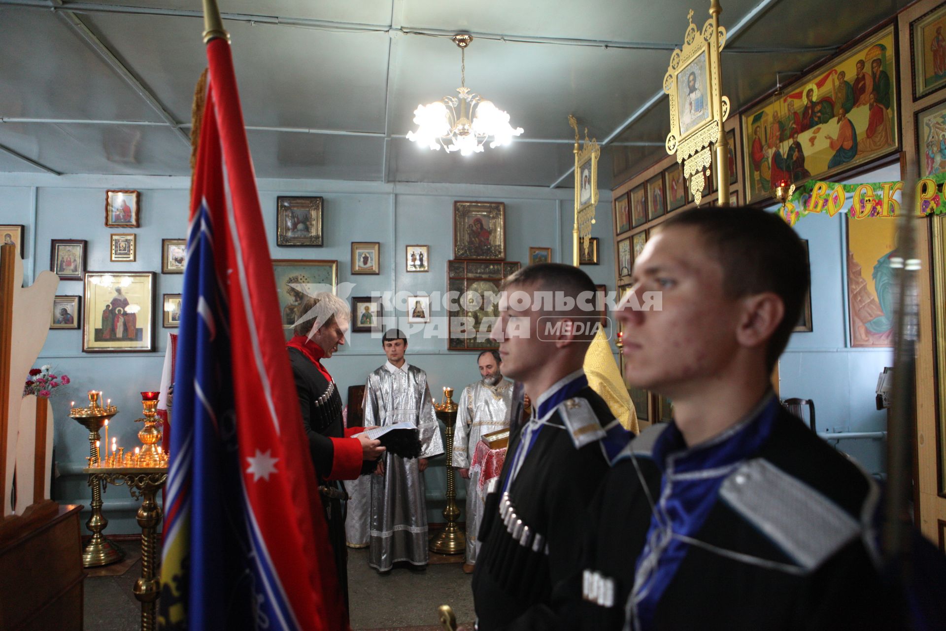 Казак Терского казачьего войска принимает присягу в сельской церкви, на переднем плане почетный караул с флагом