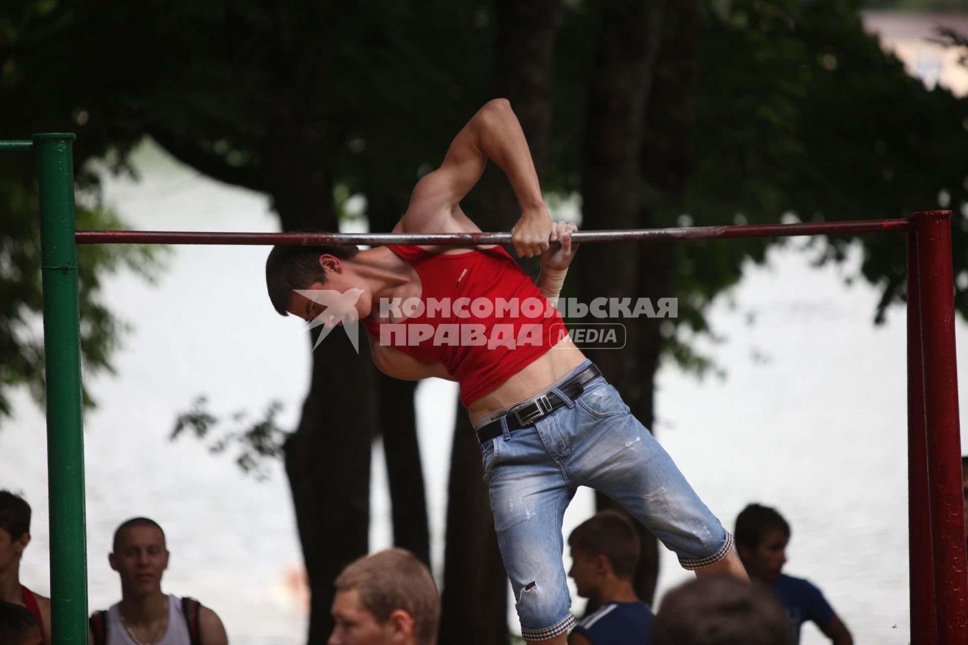 Спортсмен выполняет элементы спортивной гимнастики на турнике