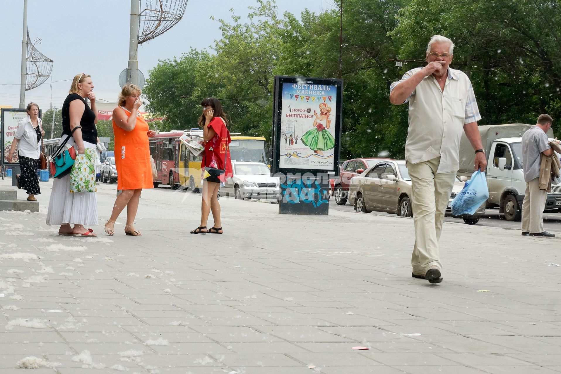 Прохожие закрывают лица от тополиного пуха.