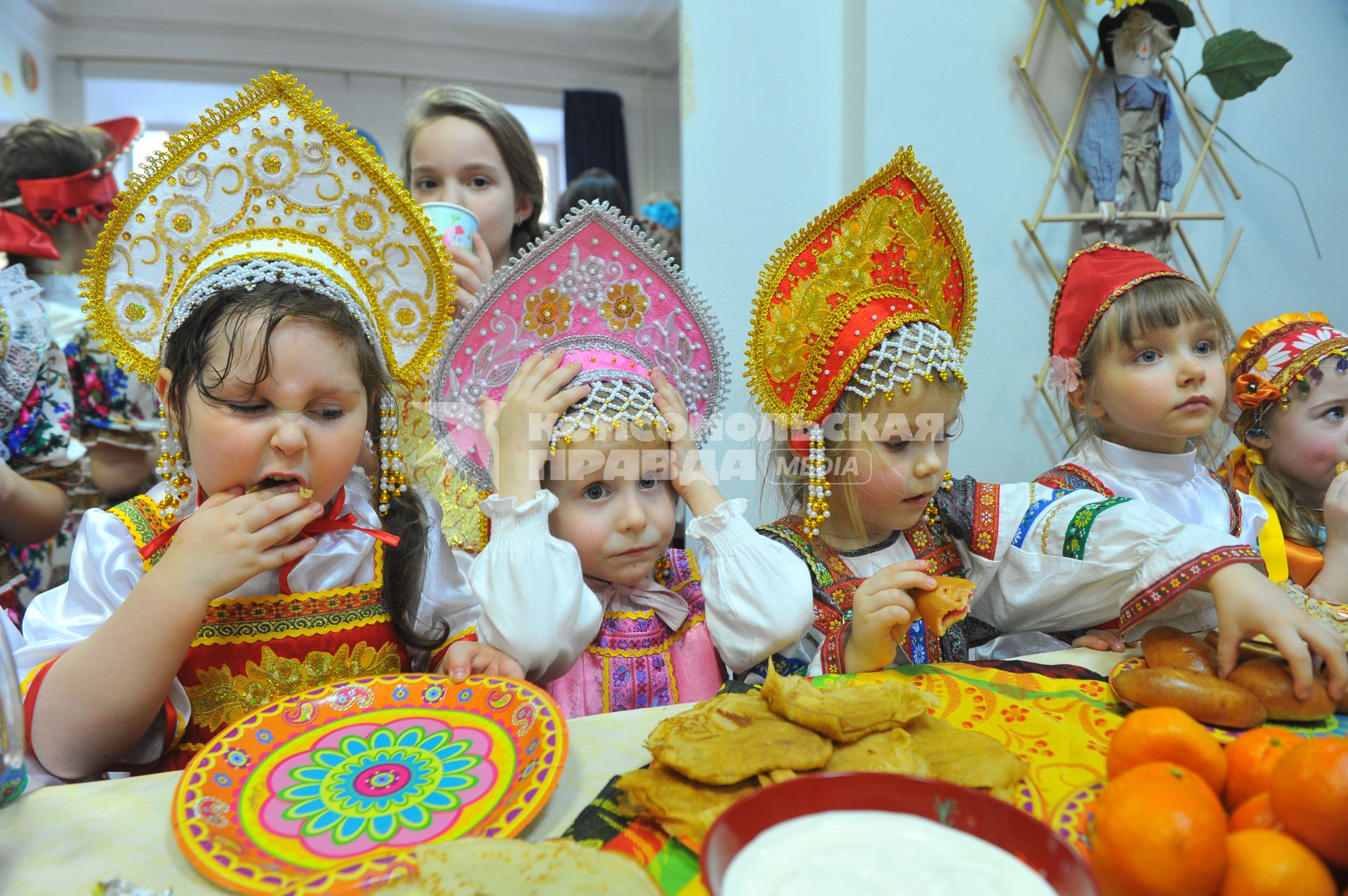 Участники коллектива `Непоседы`угощаются масленичными блинами.