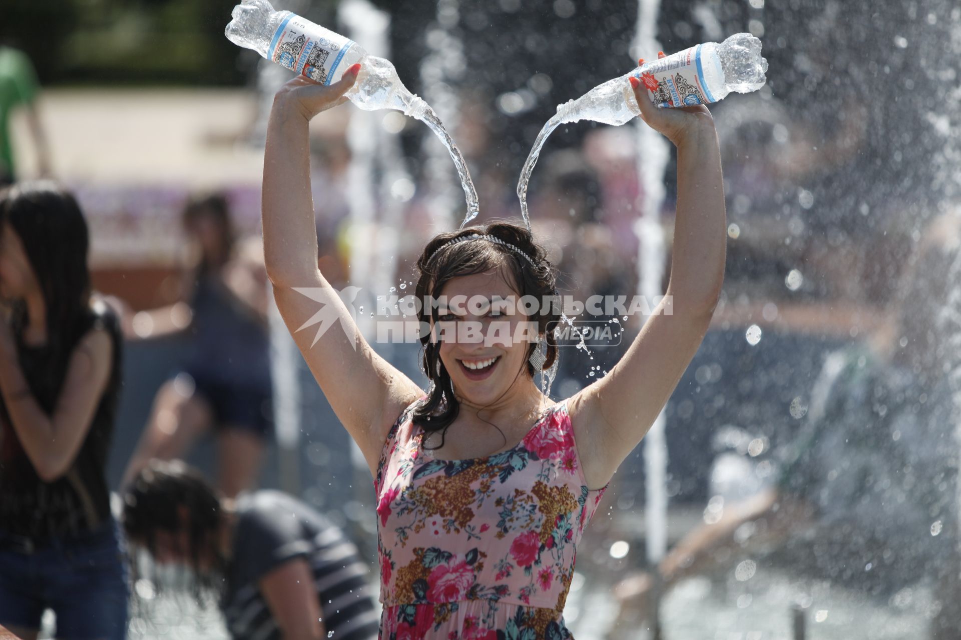 Девушка, стоя в фонтане, льет из двух бутылок воду себе на голову