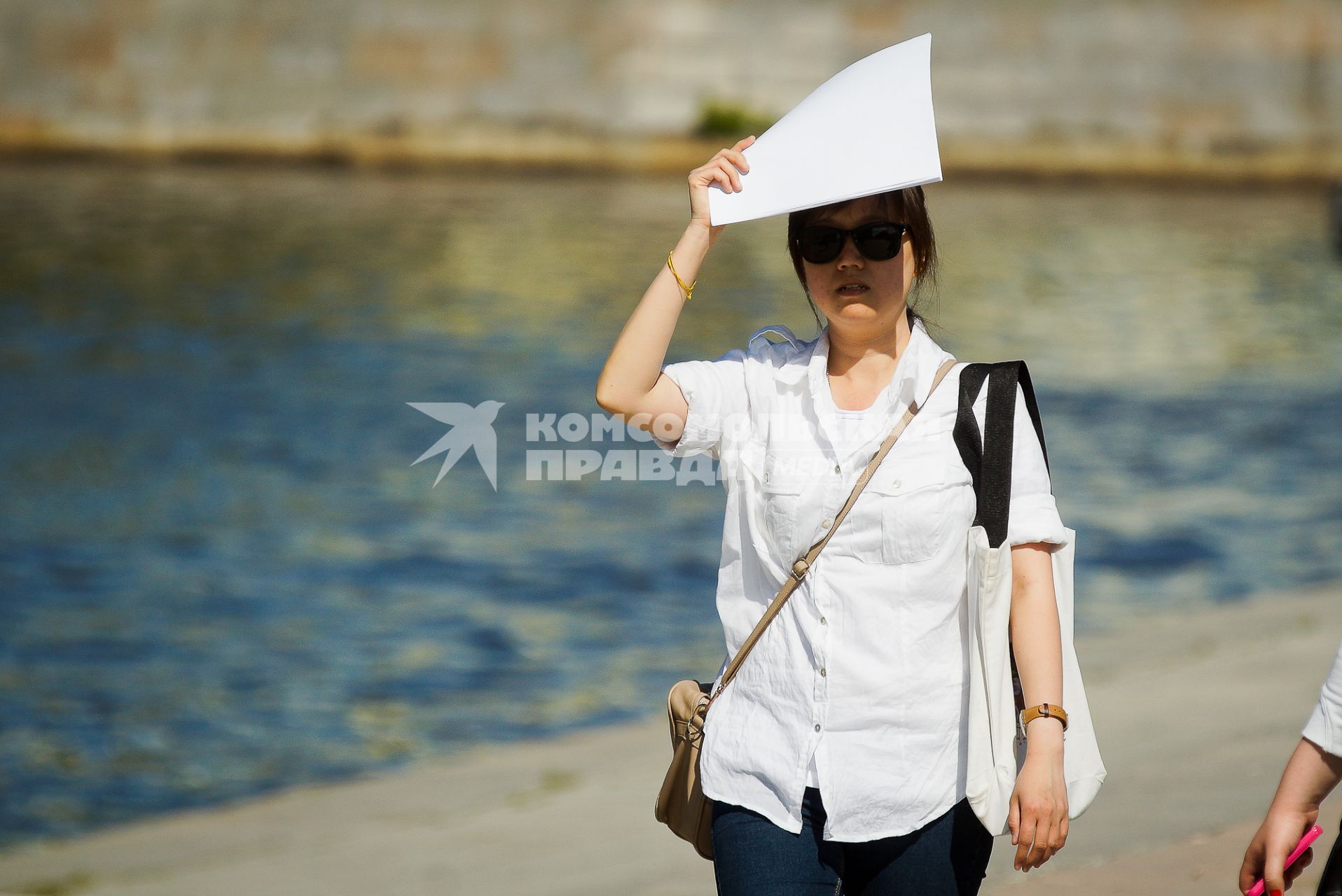 Жара. Женщина закрывает голову от солнца листом бумаги.