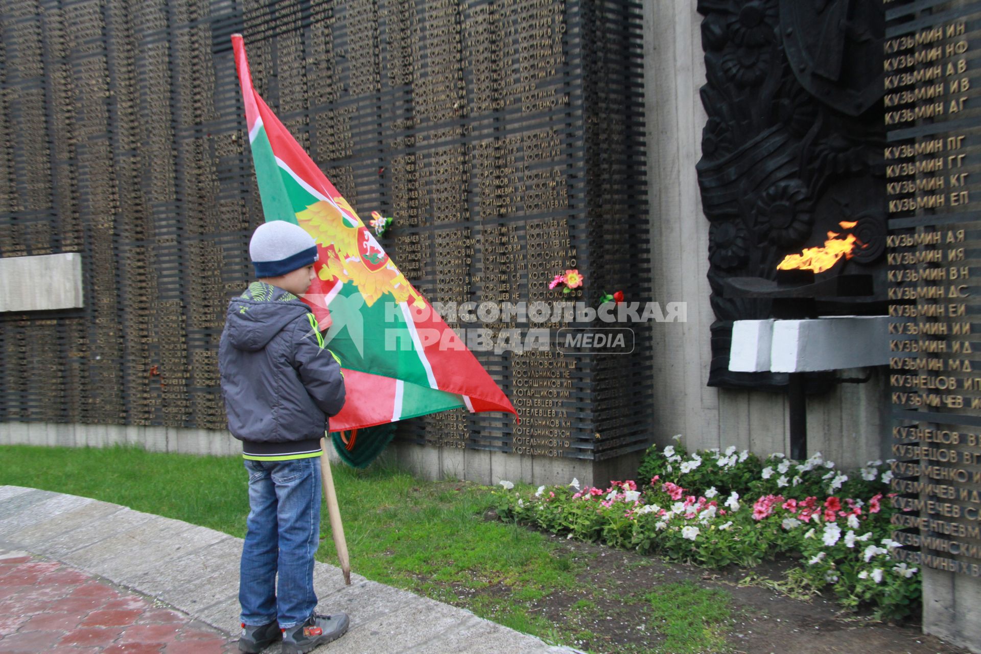 День пограничника. Ребенок с флагом пограничных войск у мемориала памяти.
