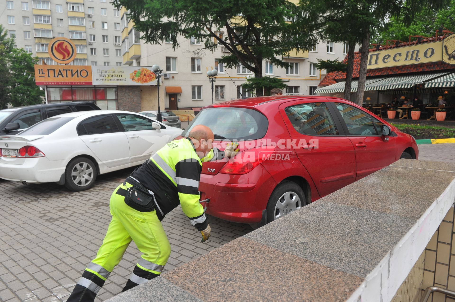 Припаркованный автомобили и сотрудник службы эвакуации `Дорожные Ангелы`.