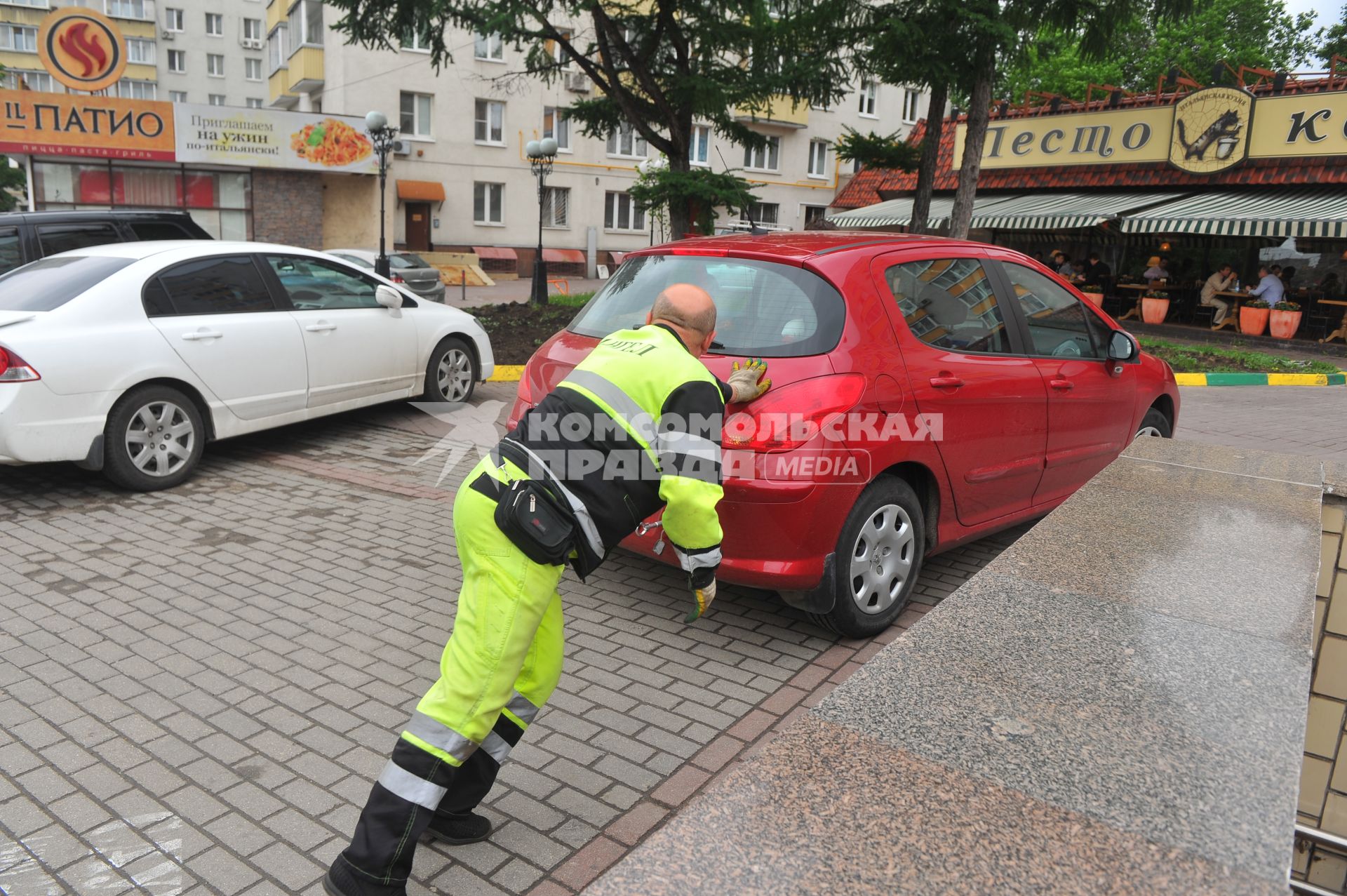 Припаркованный автомобили и сотрудник службы эвакуации `Дорожные Ангелы`.