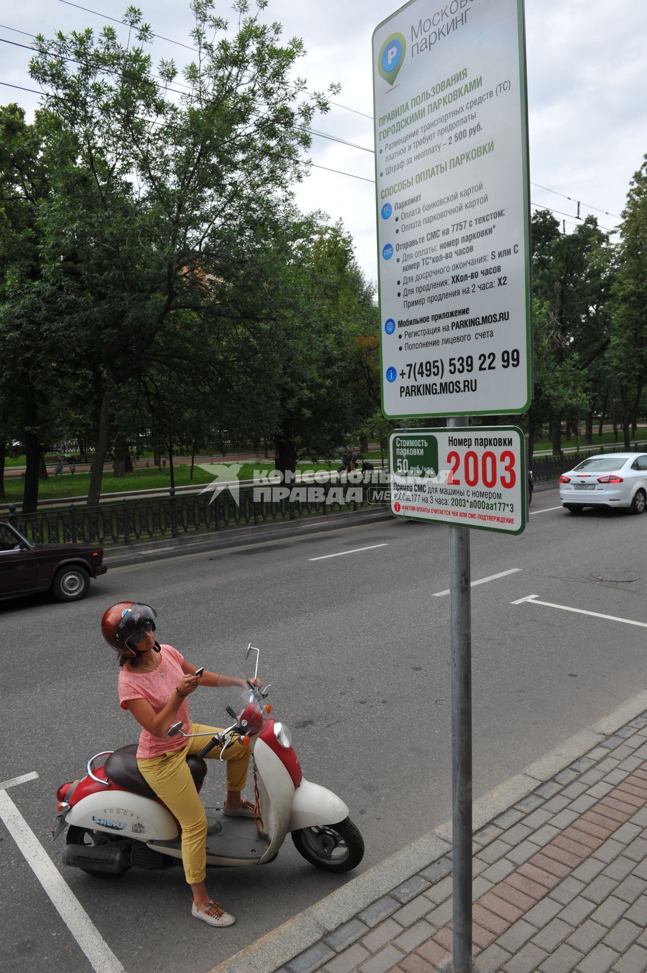 Московский паркинг. На снимке: девушка на мопеде читает правила пользования городской парковкой.