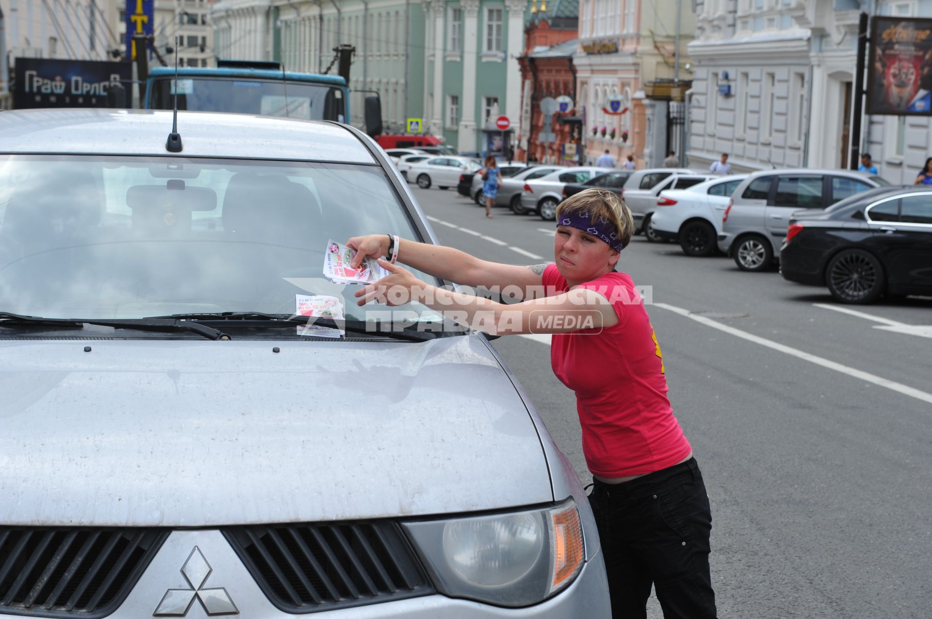 Девушка с рекламными листовками у автомобиля Mitsubishi.