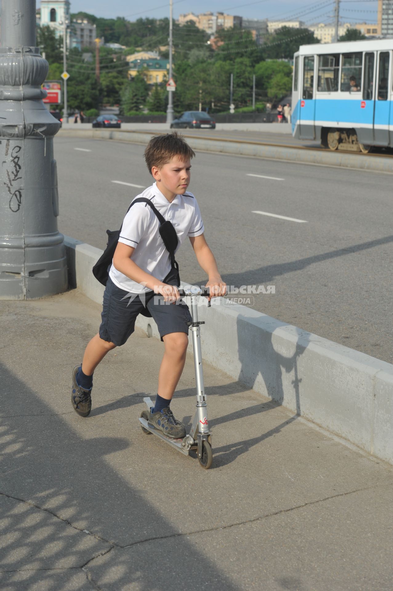 Мальчик едет на самокате.