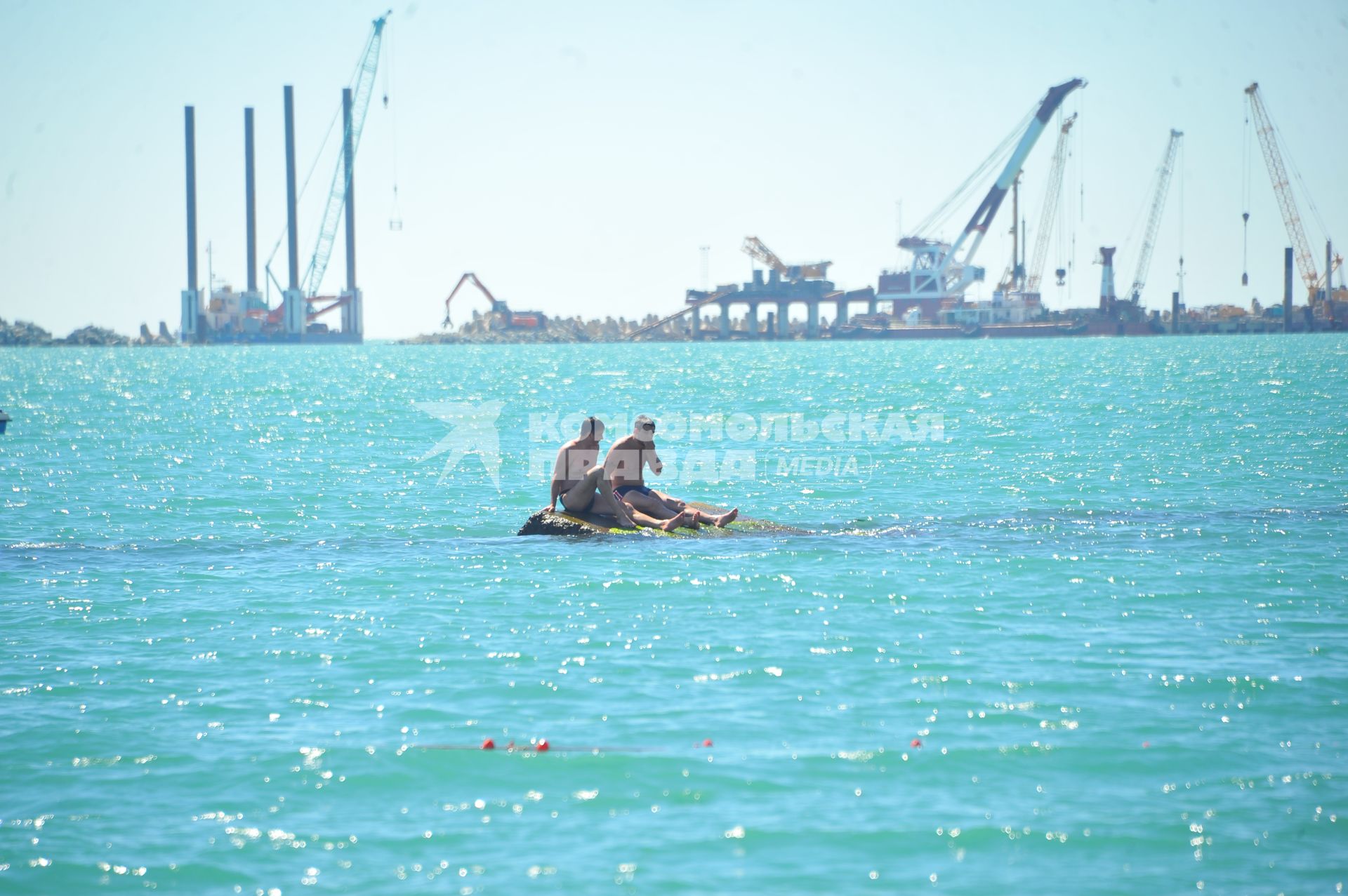 Отдых на море. На снимке: мужчины на волнорезе.