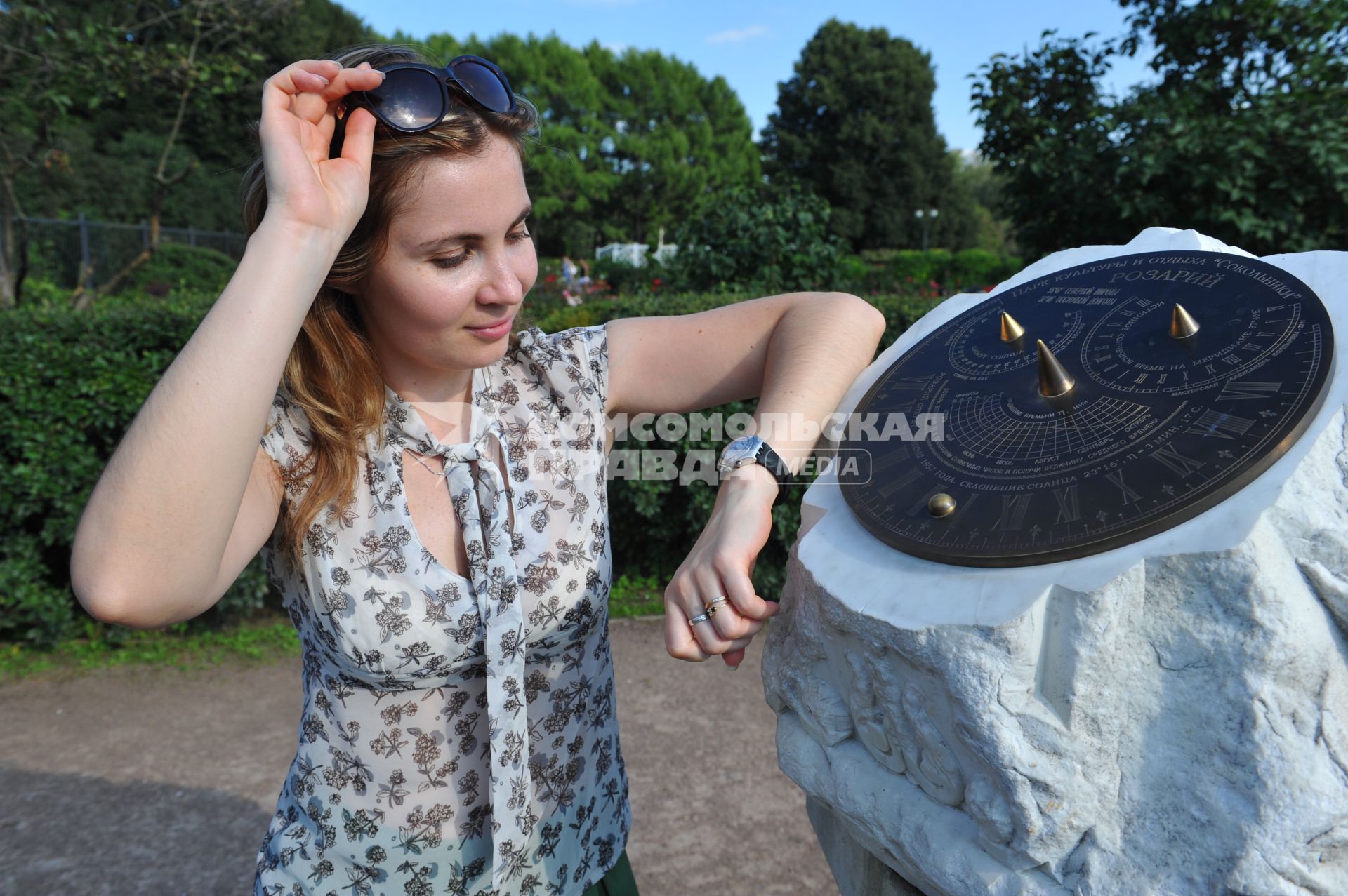 ПКиО `Сокольники`.   На снимке: часы на руке девушки и солнечные часы .