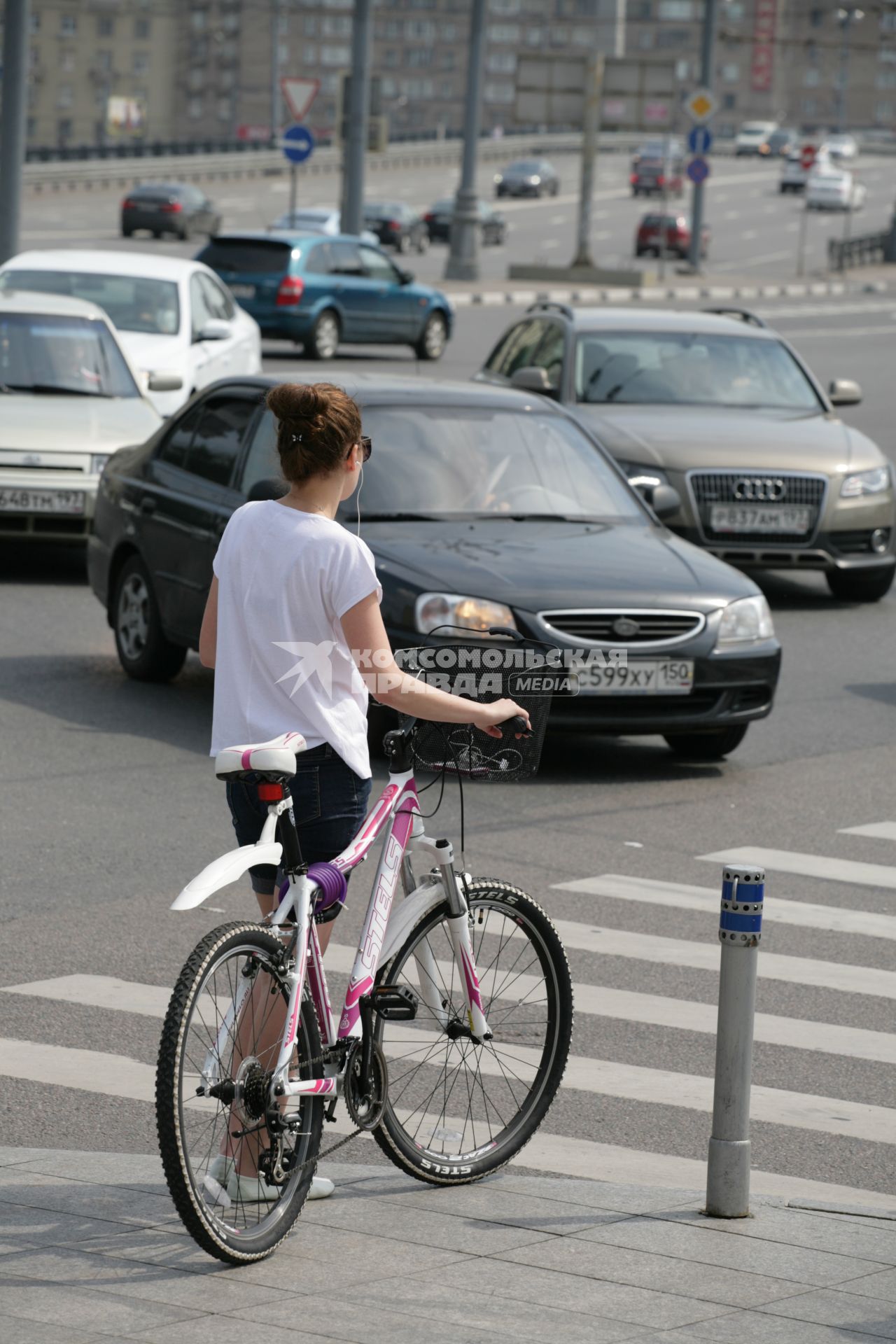 Девушка с велосипедом на пешеходном переходе.
