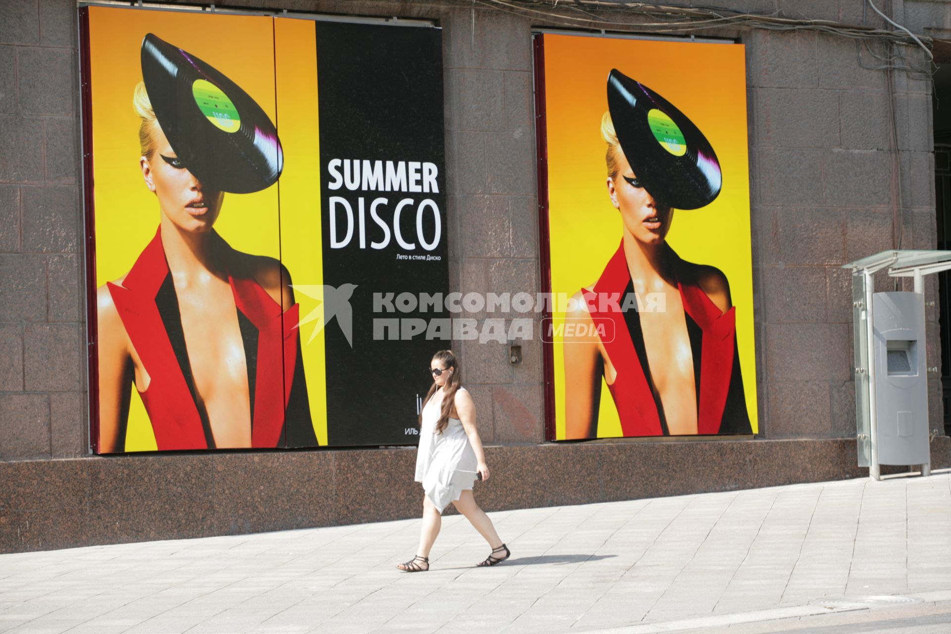 Наружная реклама. На снимке:девушка идет мимо рекалмных баннеров `Summer disco`