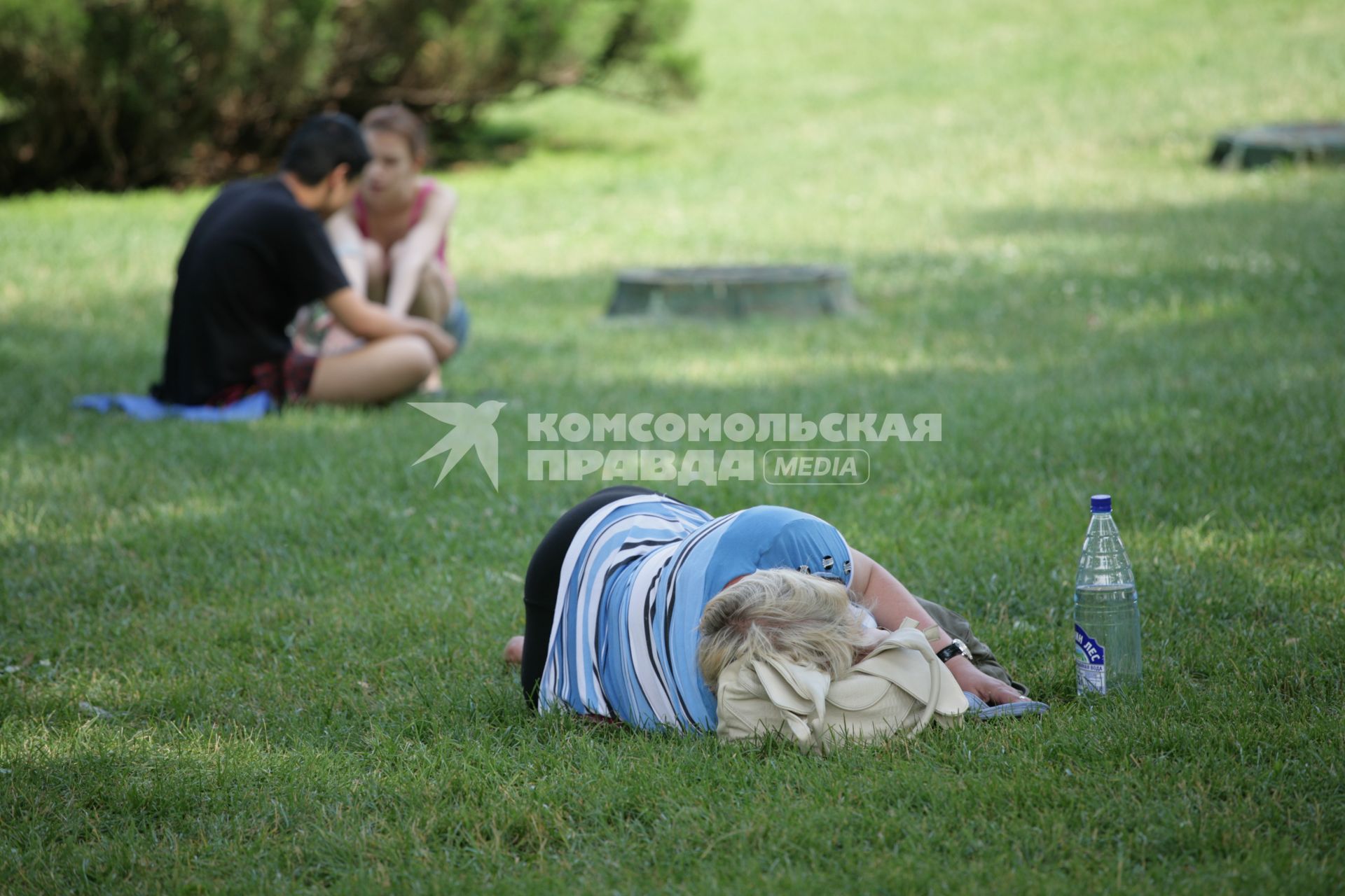 Отдыхающие в городском парке. На снимке: женщина спит на лужайке.