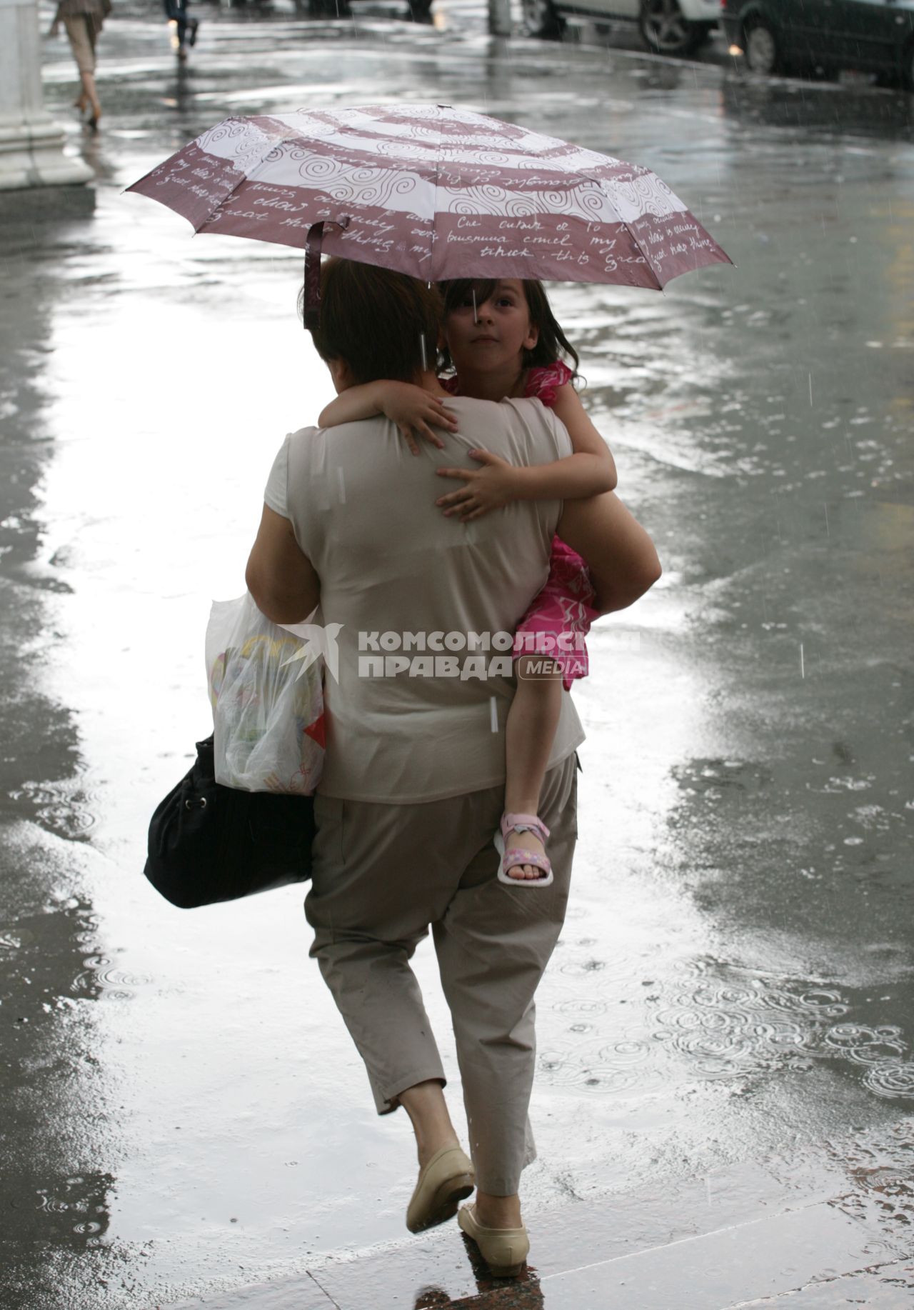 Дождь в городе. На снимке: женщина с ребенком  под зонтом.