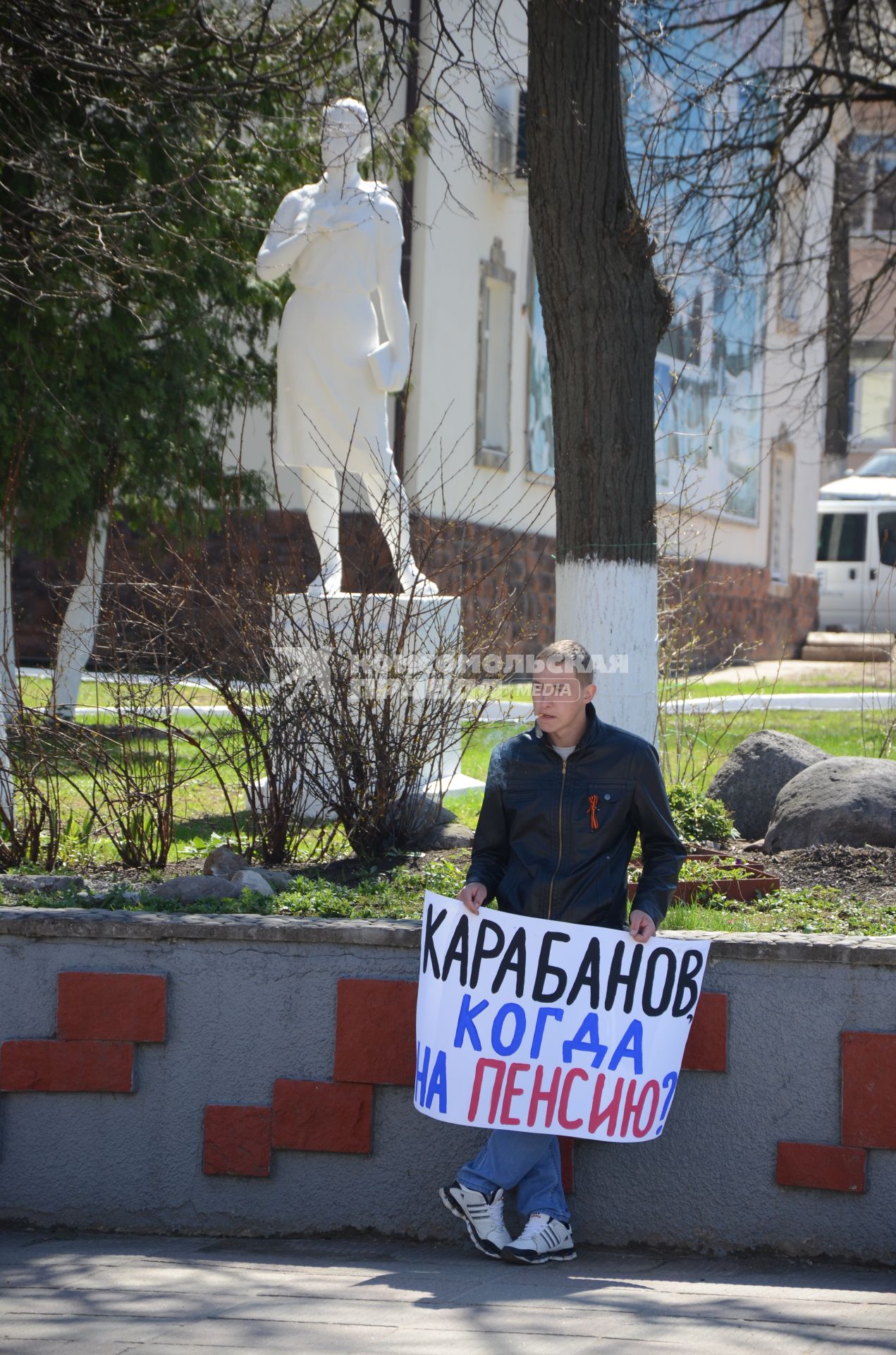 Мужчина держит плакат `Карабанов, когда на пенси?`.