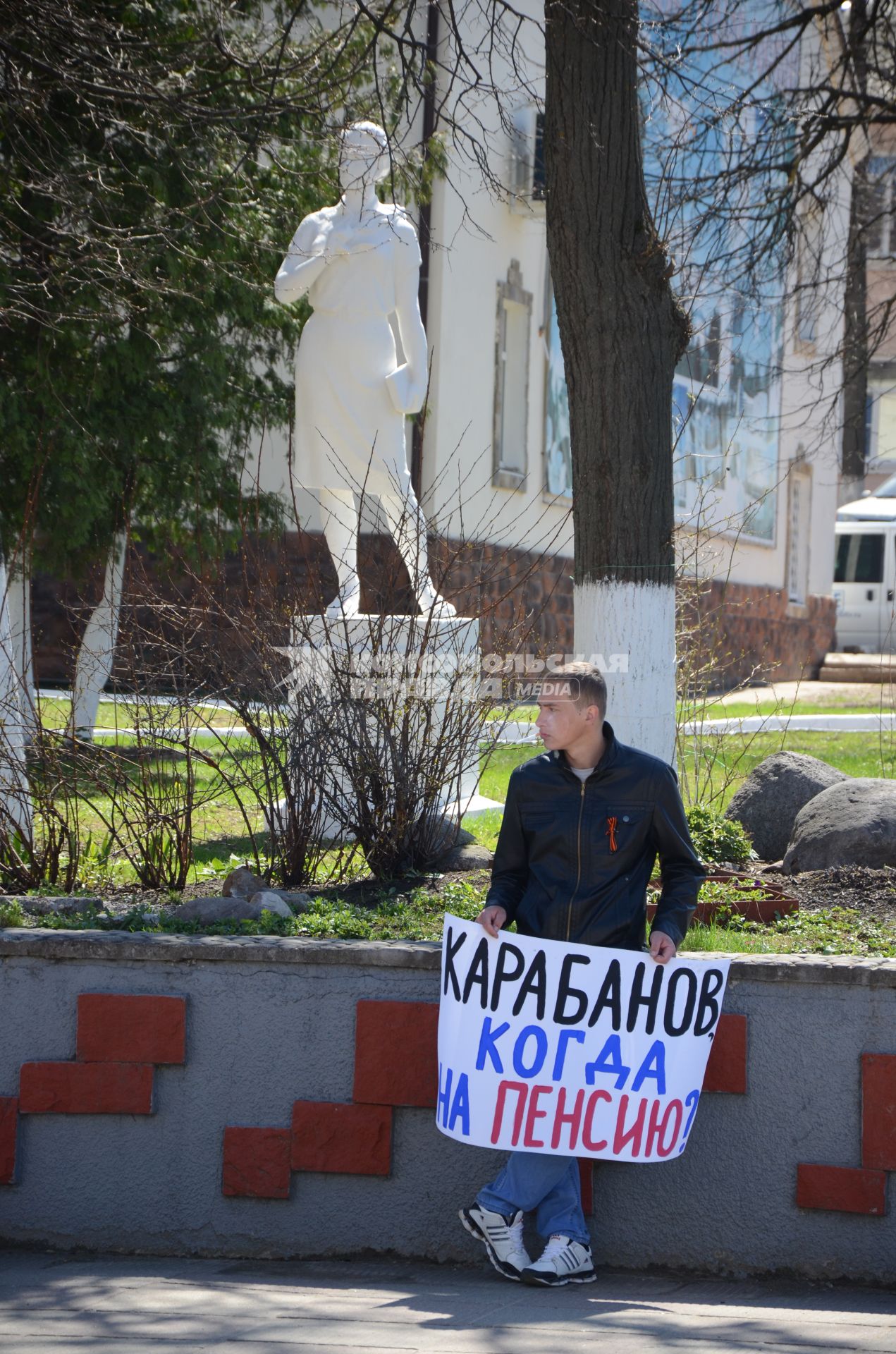 Мужчина держит плакат `Карабанов, когда на пенси?`.