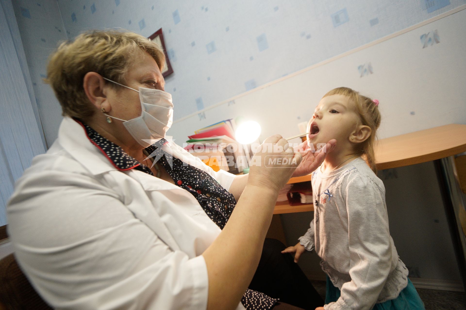 Медицинский осмотр детей в детском садике. На снимке: медицинский сотрудник проверяет горло ребенку.