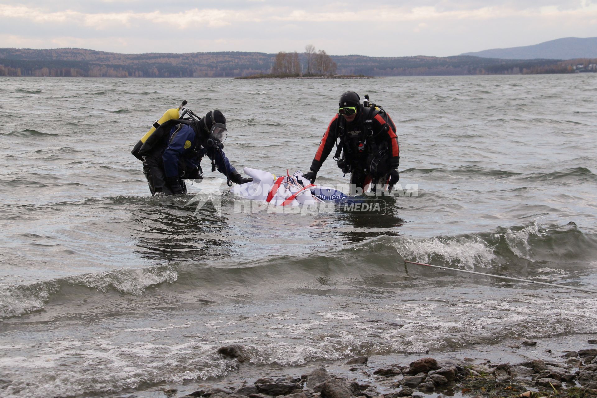 Водолазы вытаскивают из воды метеорит с помощью лебедки.