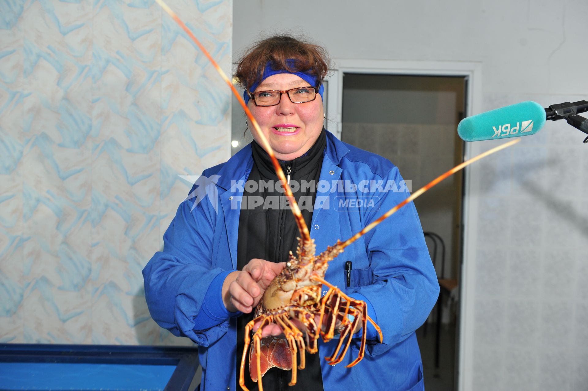 Профессиональная продажа морепродуктов и охлажденной рыбы. Склад рыбной продукции компании  `La Maree`.  На снимке: женщина держит  омара.