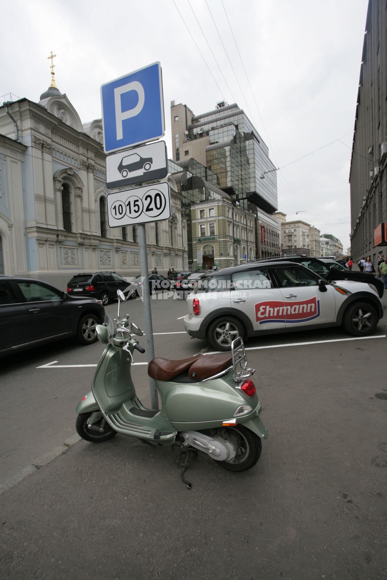 Припаркованный скутер у дорожного знака `Платная стоянка`