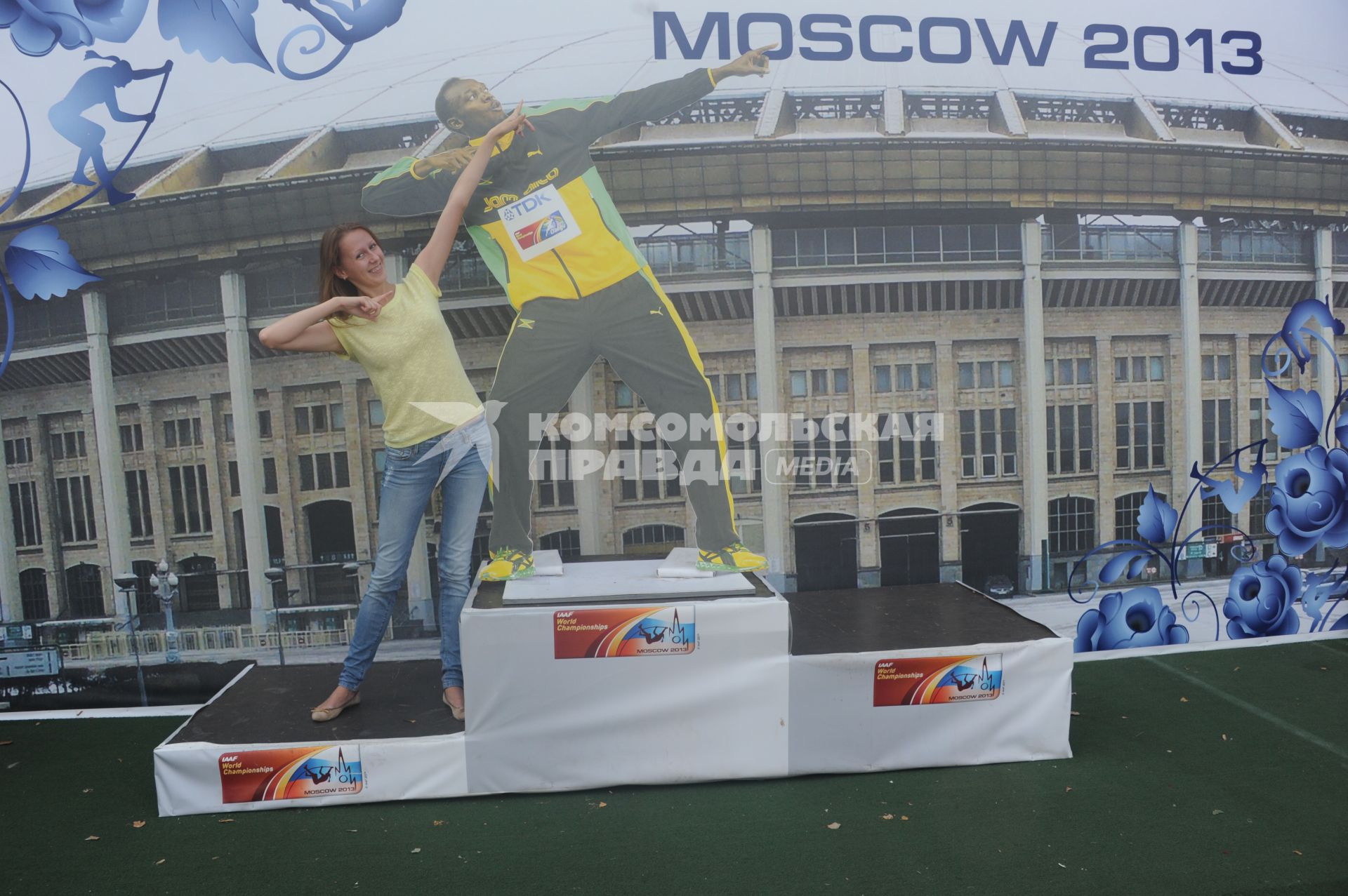 СК `Лужники`.  Чемпионат мира по легкой атлетике 2013.    На снимке: девушка на пьедестале рядом с  картонной фигурой ямайского спортсмена Усэйна Болта