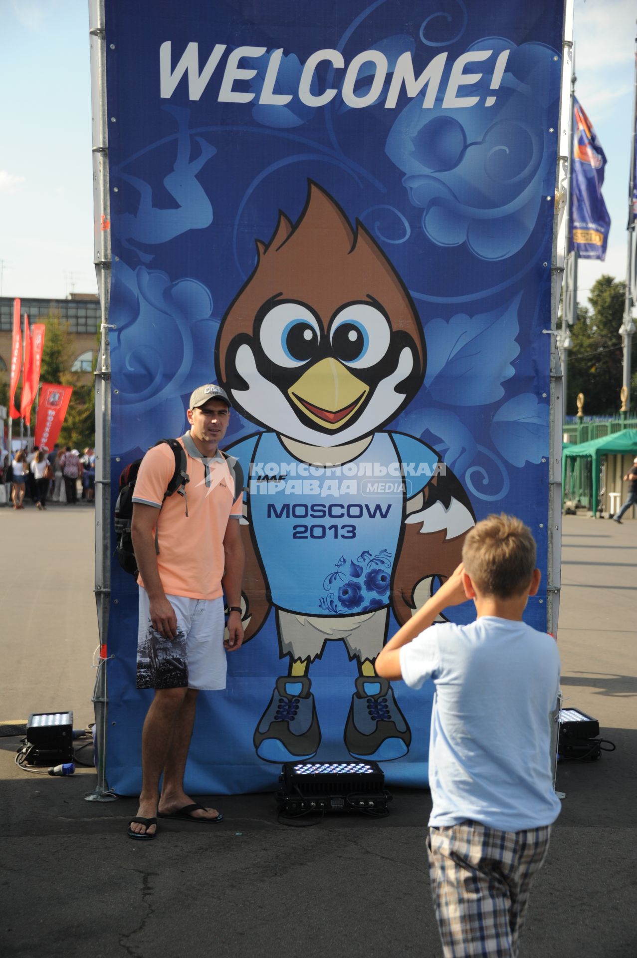 СК `Лужники`. Чемпионат мира по легкой атлетике 2013. На снимке: мальчик фотографирует мужчину на фоне рекламного стенда `Welcome!`