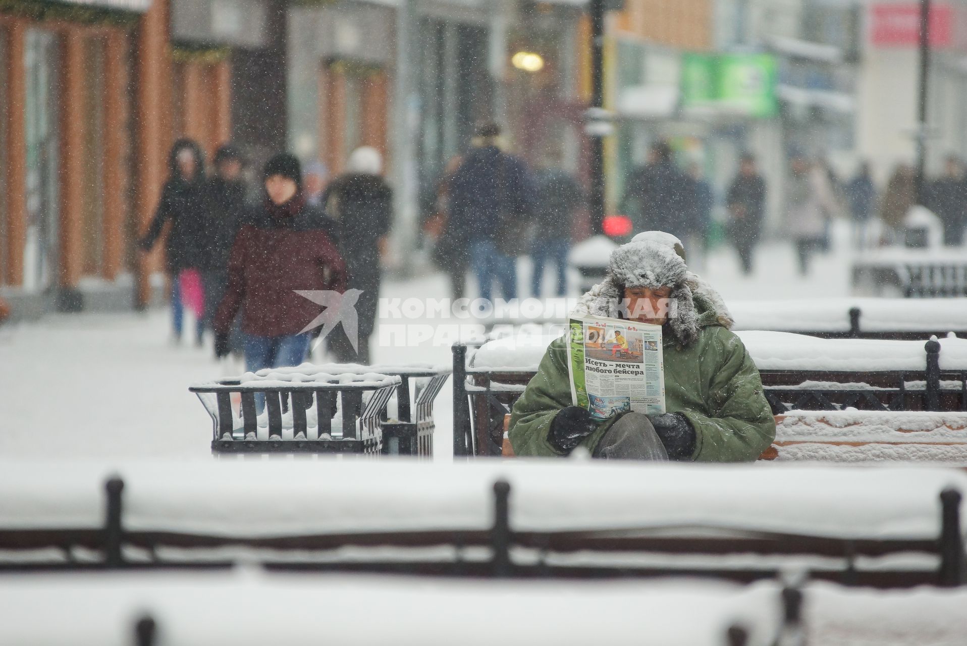 Снегопад в Екатеринбурге. На снимке: мужчина сидя на лавочке читает журнал.