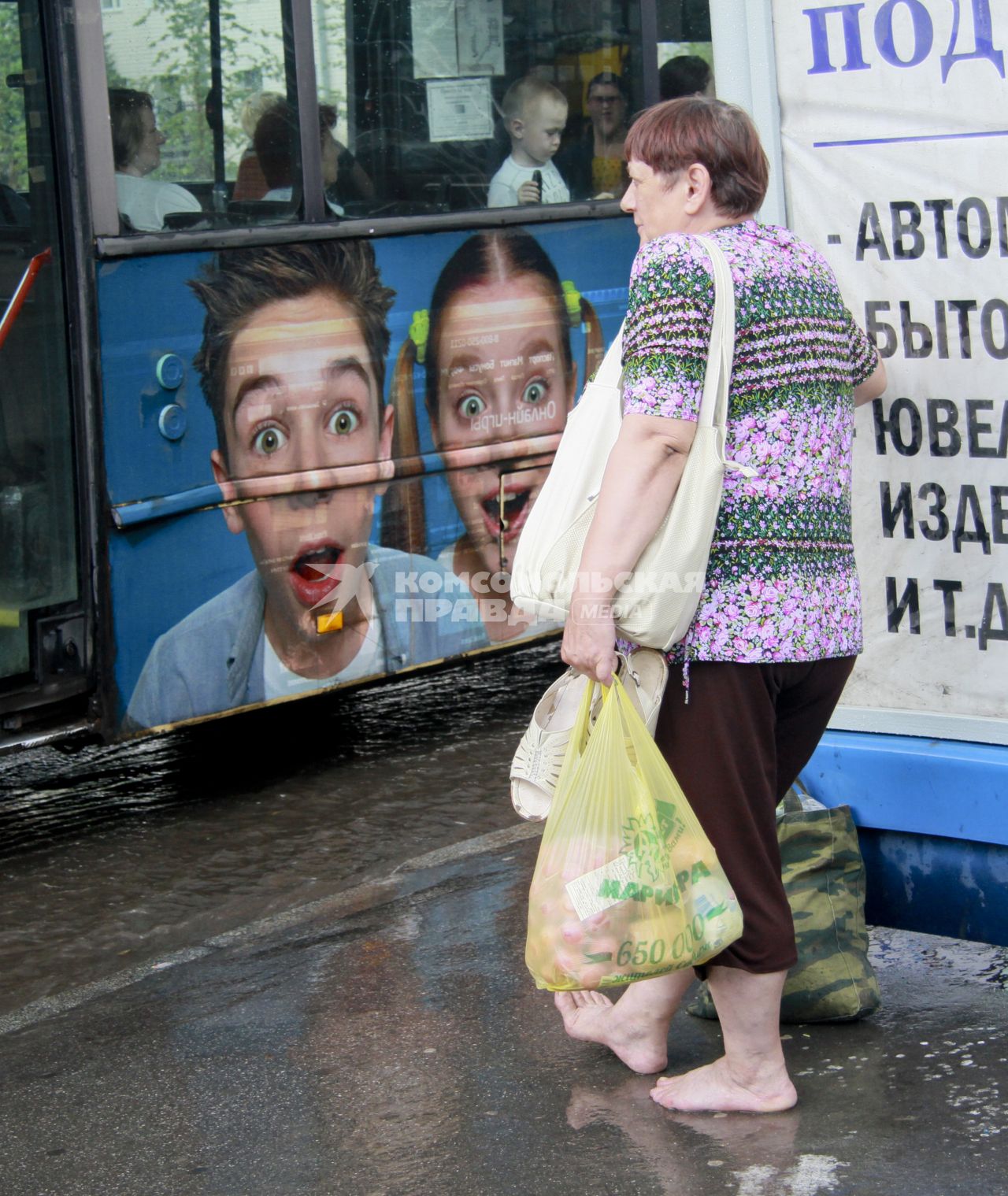 Женщина  стоит босиком на остановке общественного транспорта.