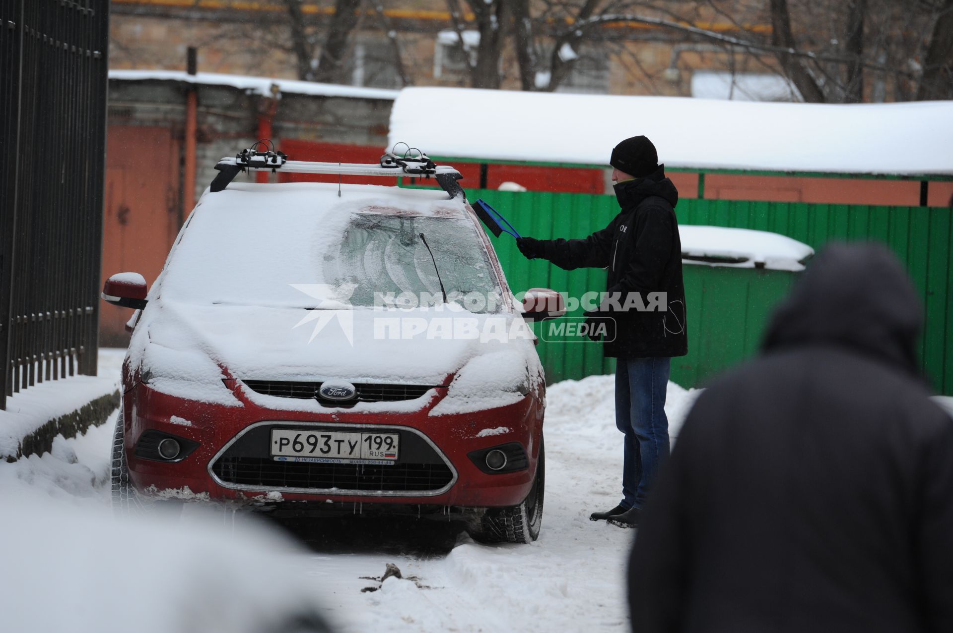 Мужчина очищает автомобиль от снега.