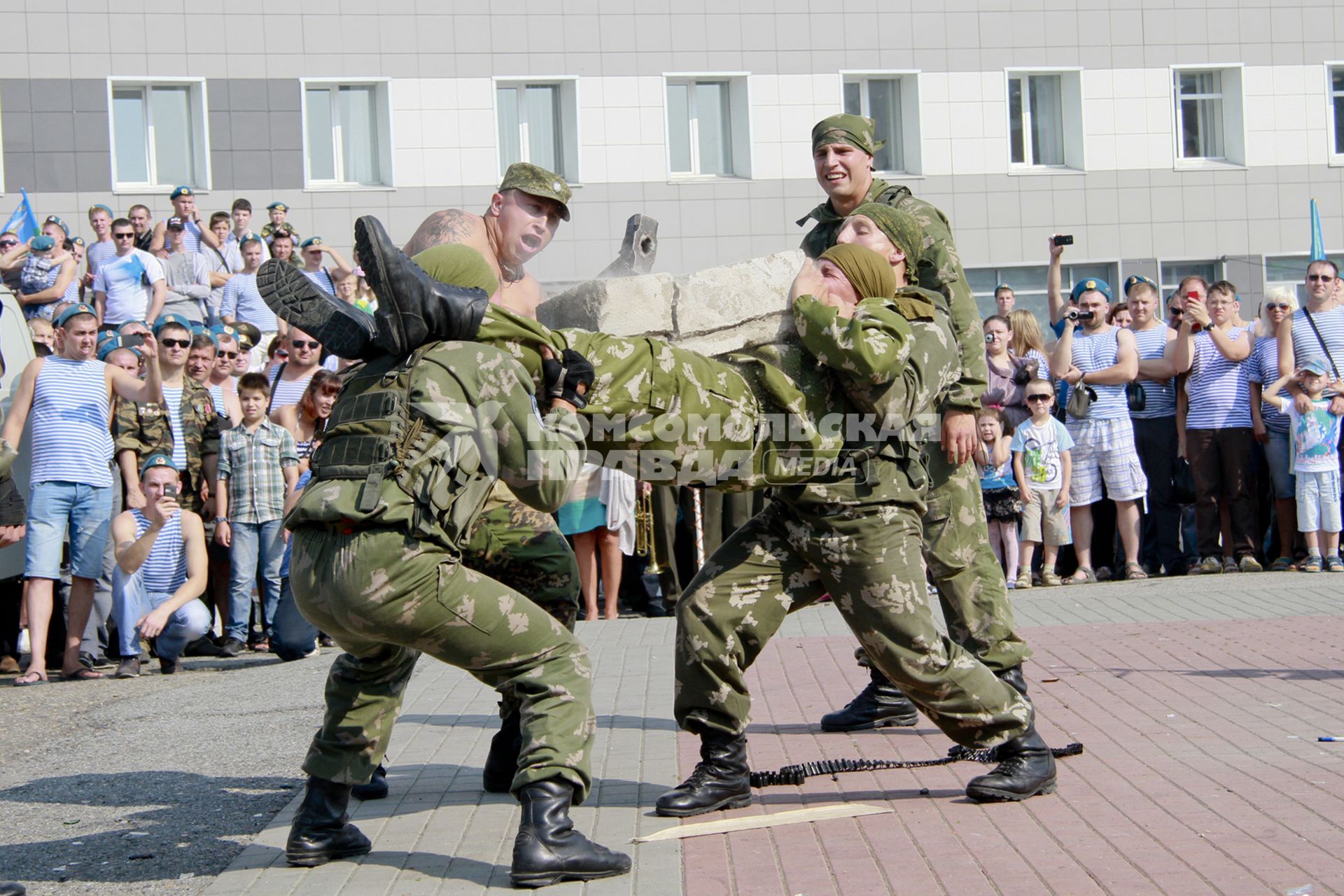 День ВДВ. Военнослужащие исполняют показательные выступления, кувалдой ломают бетонные блоки на животе сослуживцев.