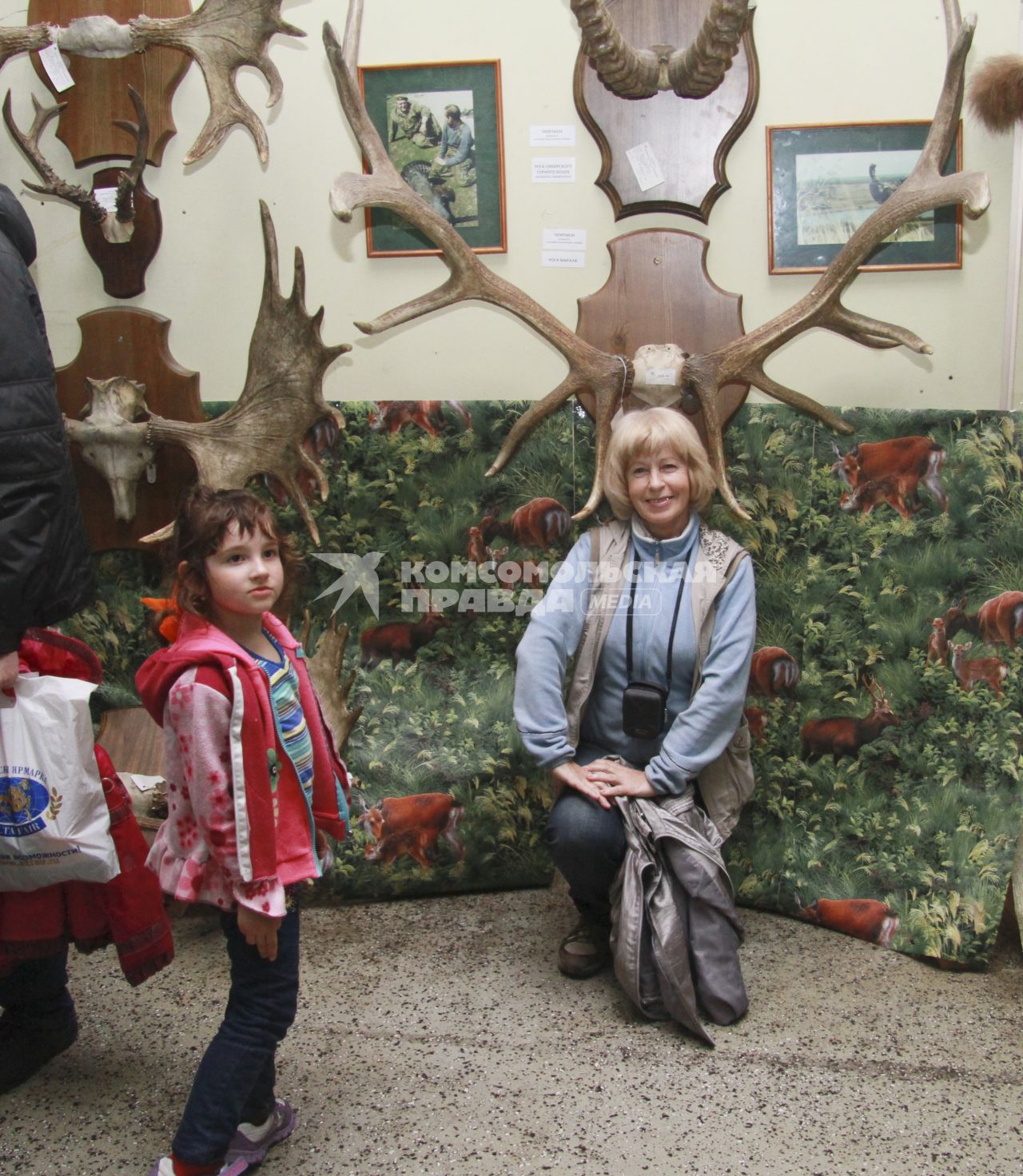 Выставка `Животный мир Алтая`. Женщина фотографируется с рогами лося.