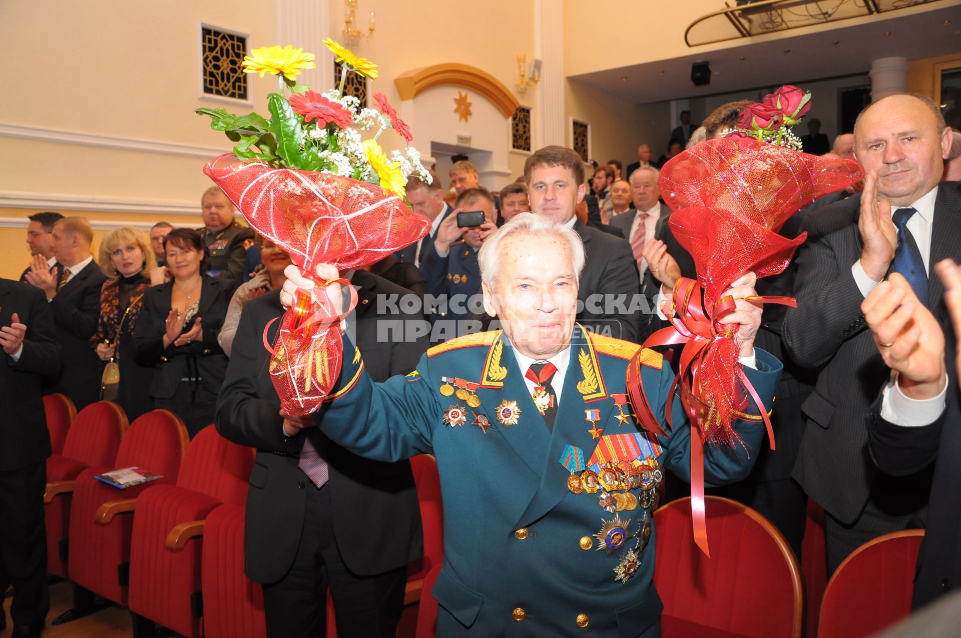 Конструктор стрелкового оружия Михаил Калашников в парадной форме с букетами цветов.