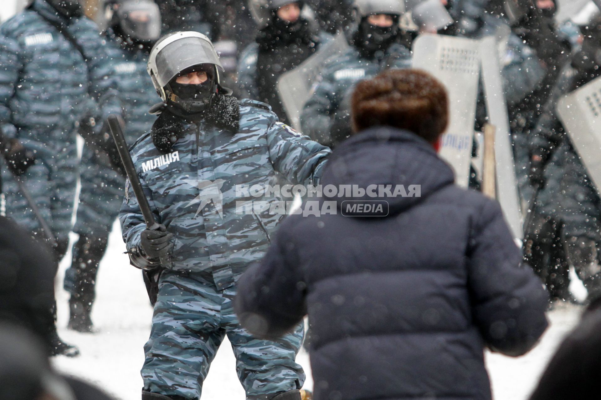 Сотрудник милиции с дубинкой напротив протестующих.