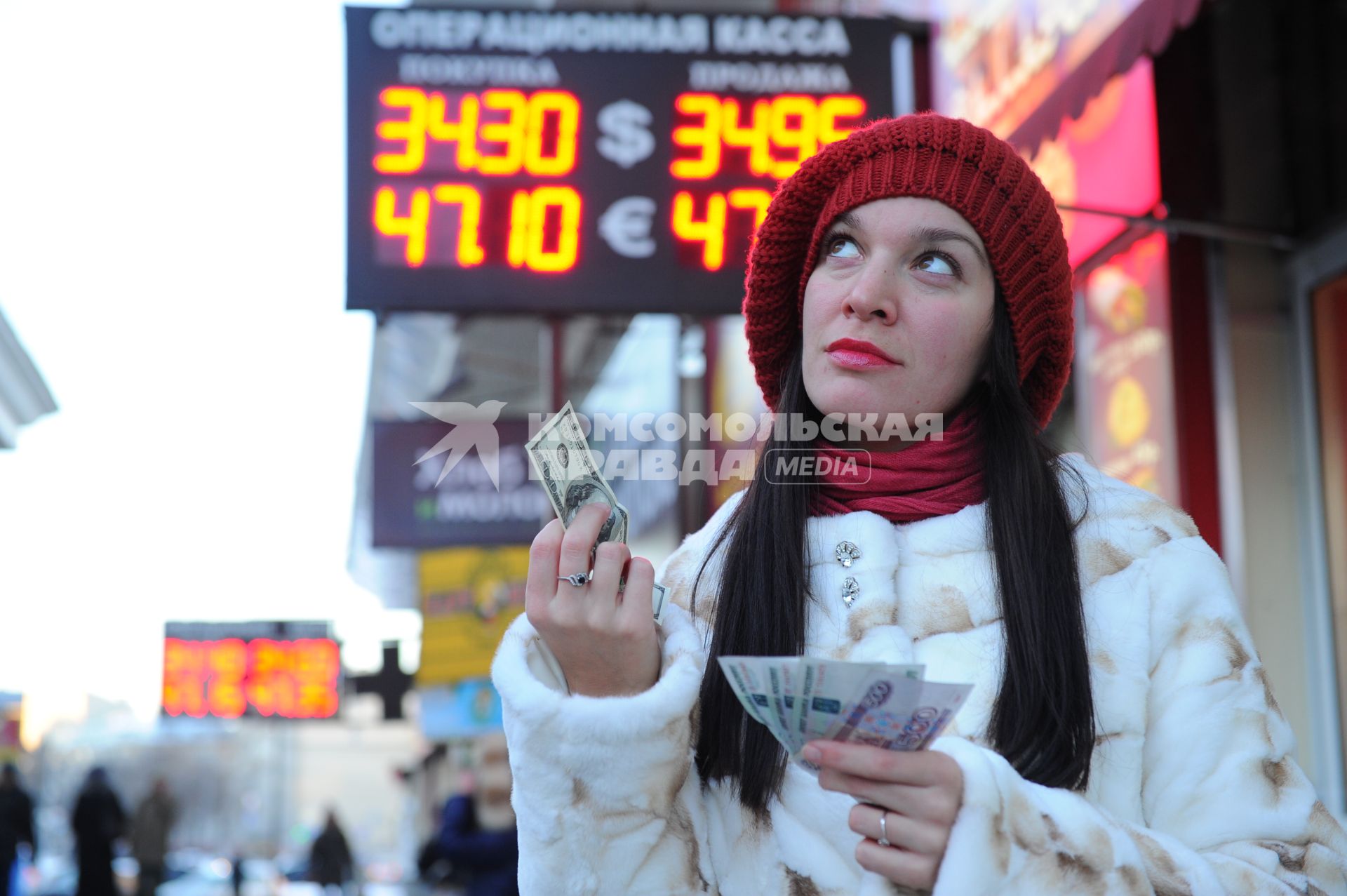 Девушка с деньгами около пункта обмена валюты.
