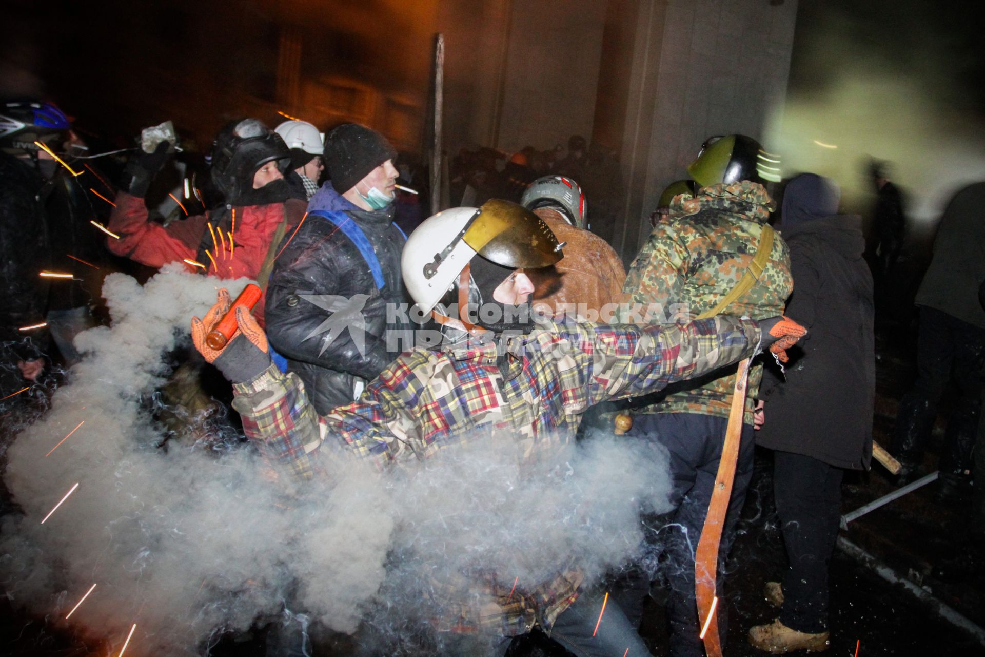 Протестующие штурмуют Украинский дом. На снимке: протестующий бросает питарду.