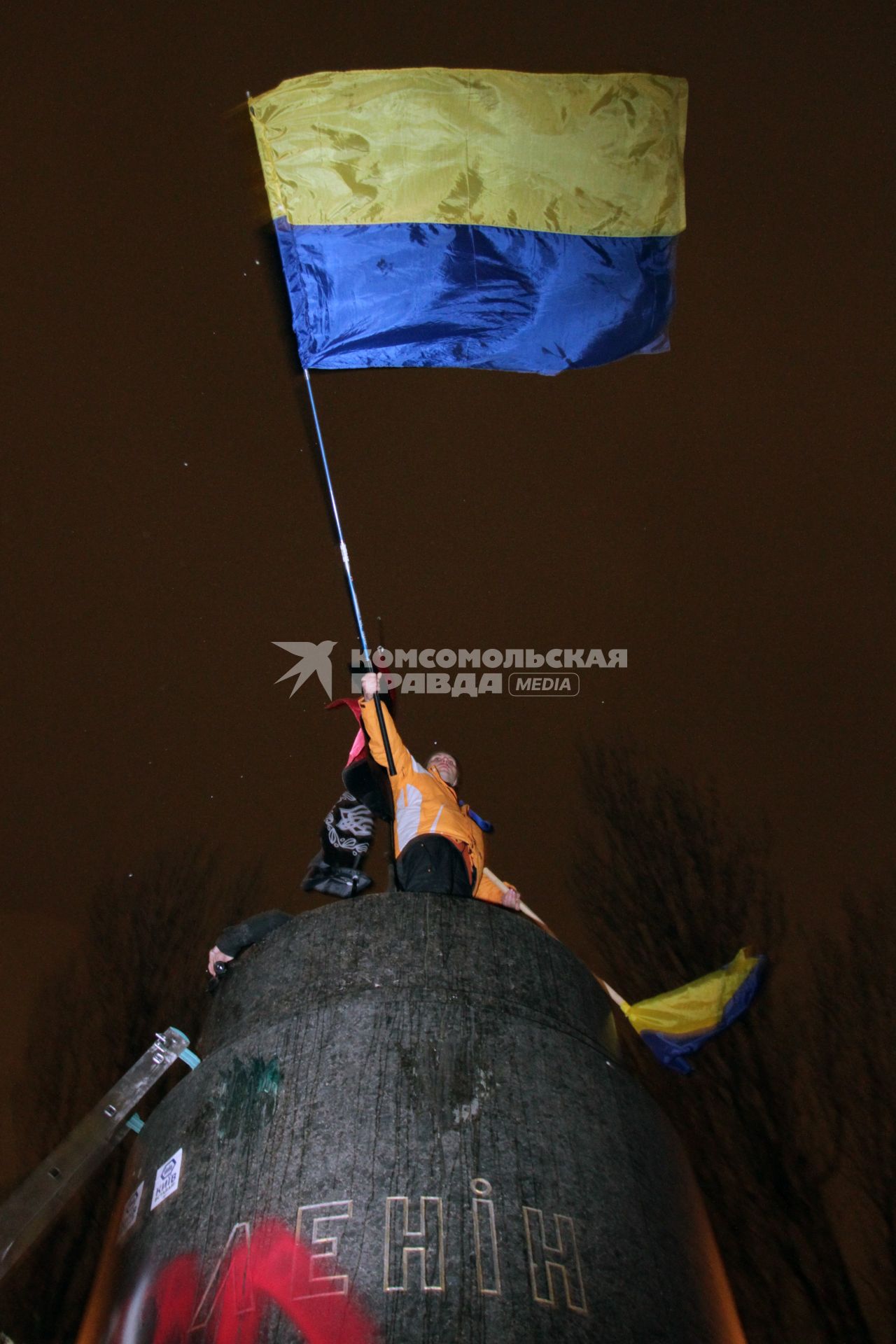 Протестующий с украинским флагом на постаменте памятника В. Ленину.